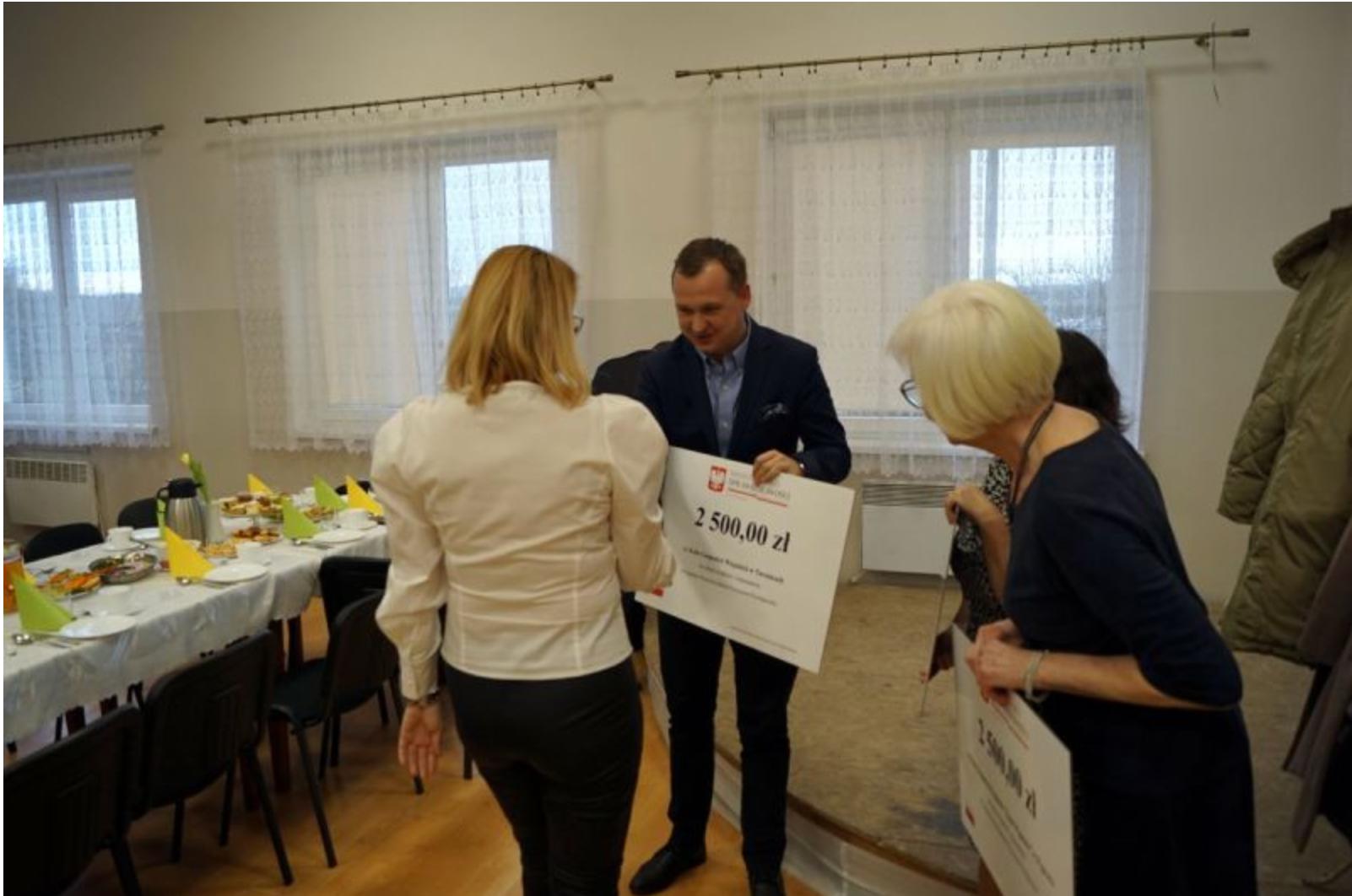 Mariusz Kałużny uroczyście przekazuje voucher