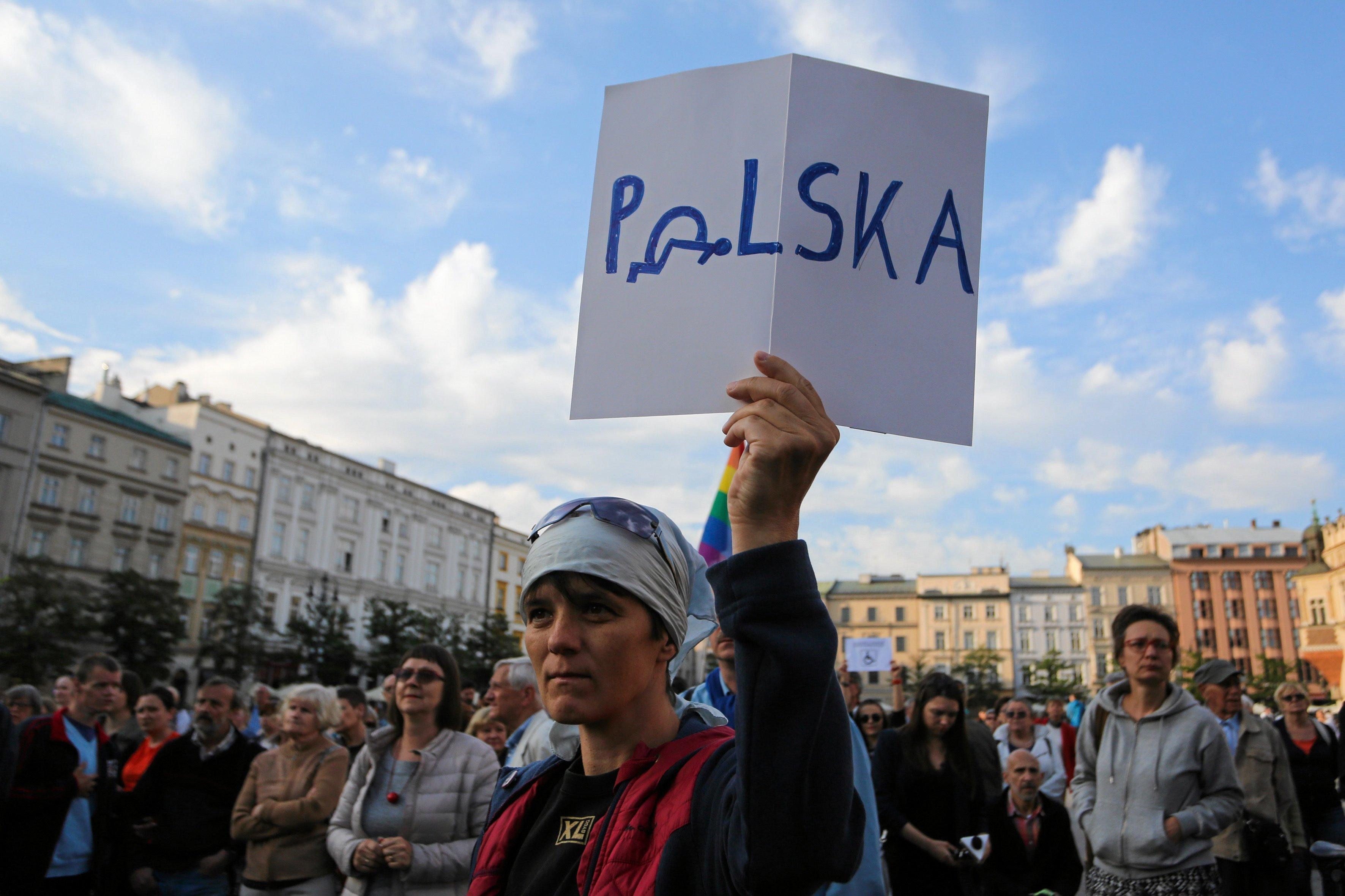 Uczestniczka protestu podnosi kartkę ze słowem „Polska”, zamiast litery o widać symbol przewróconego wózka inwalidzkiego