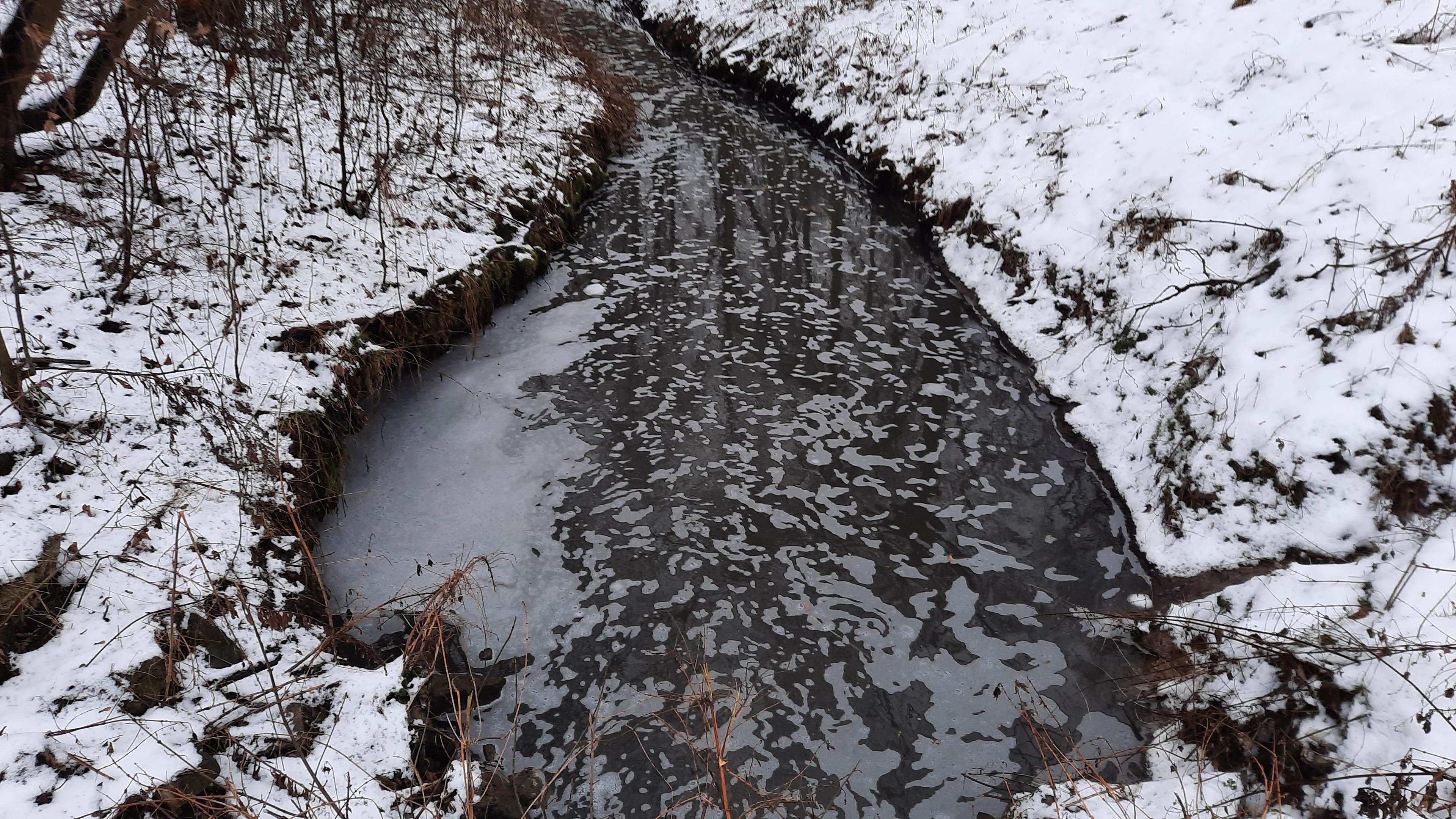 zanieczyszcony potok, brzegi pokryte sniegiem