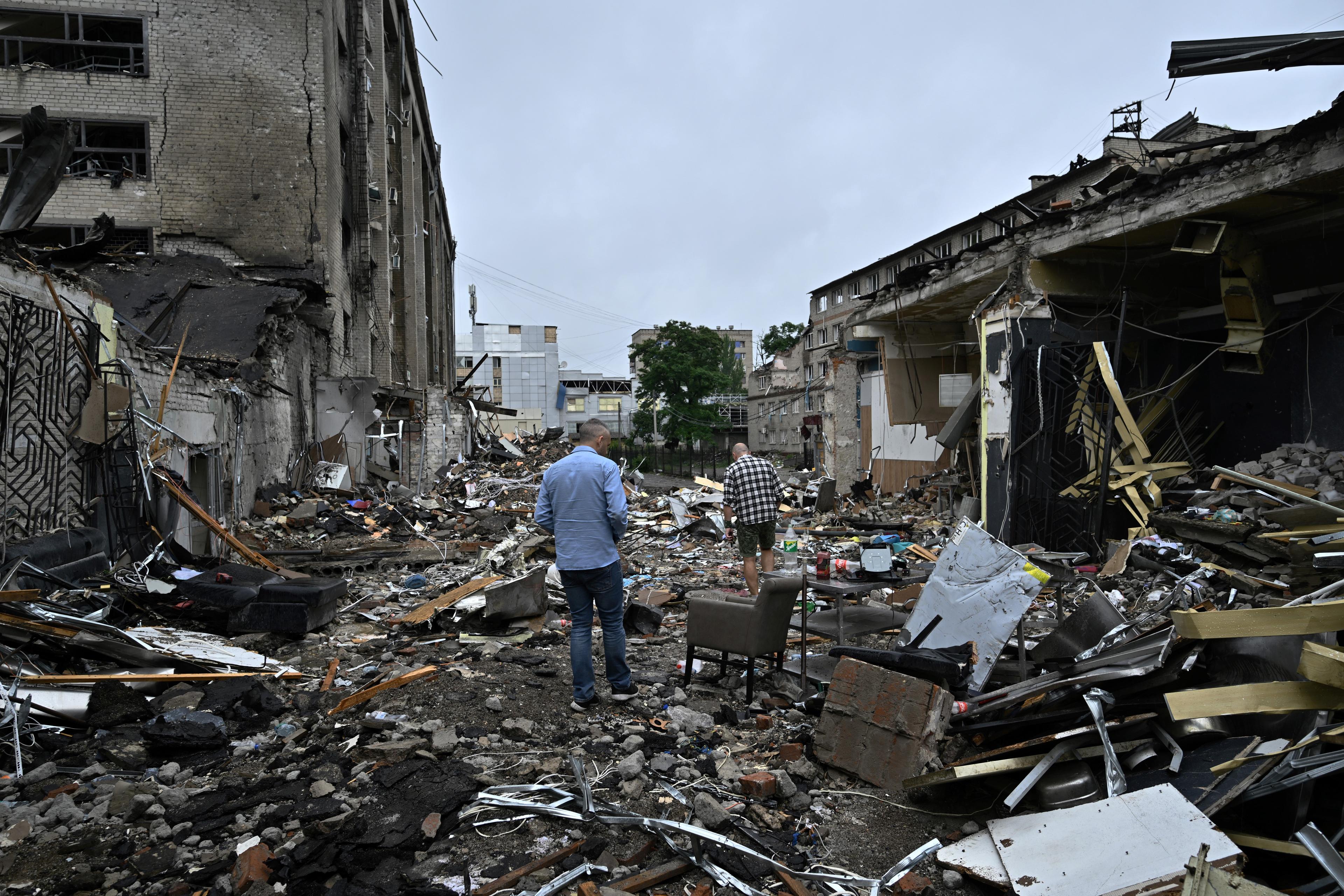 Local residents walk among debris following a Russian missile strike in the center of Kramatorsk on June 29, 2023, amid the Russian invasion of Ukraine. - The toll from a Russian missile strike on a restaurant in eastern Ukraine rose to 12 dead and at least 60 wounded on June 28, 2023 morning, including children, as the Kremlin insisted Russian forces only hit military-linked targets. (Photo by Genya SAVILOV / AFP)