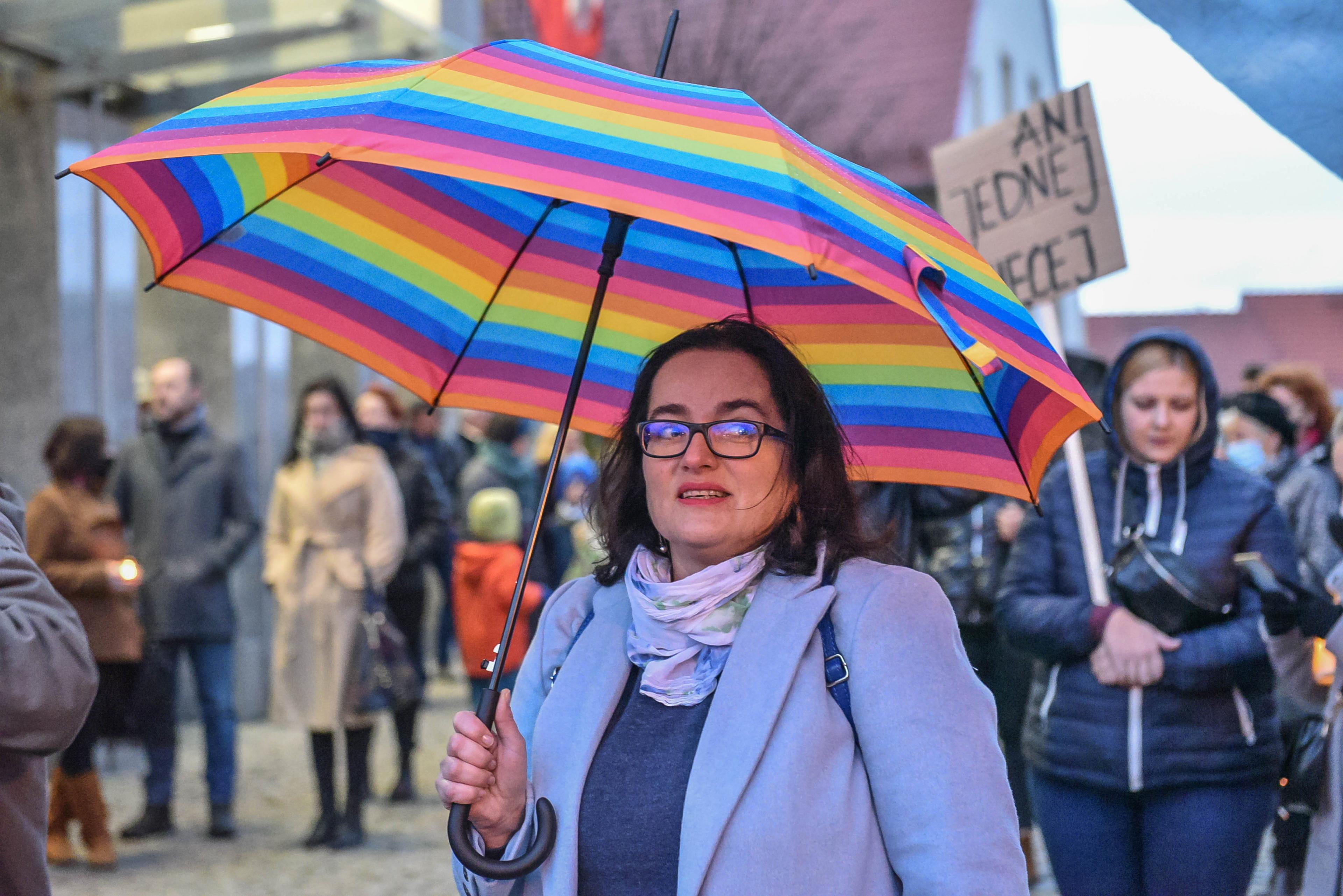ciemnowłosa kobieta w okularach stoi pod kolorowym parasolem