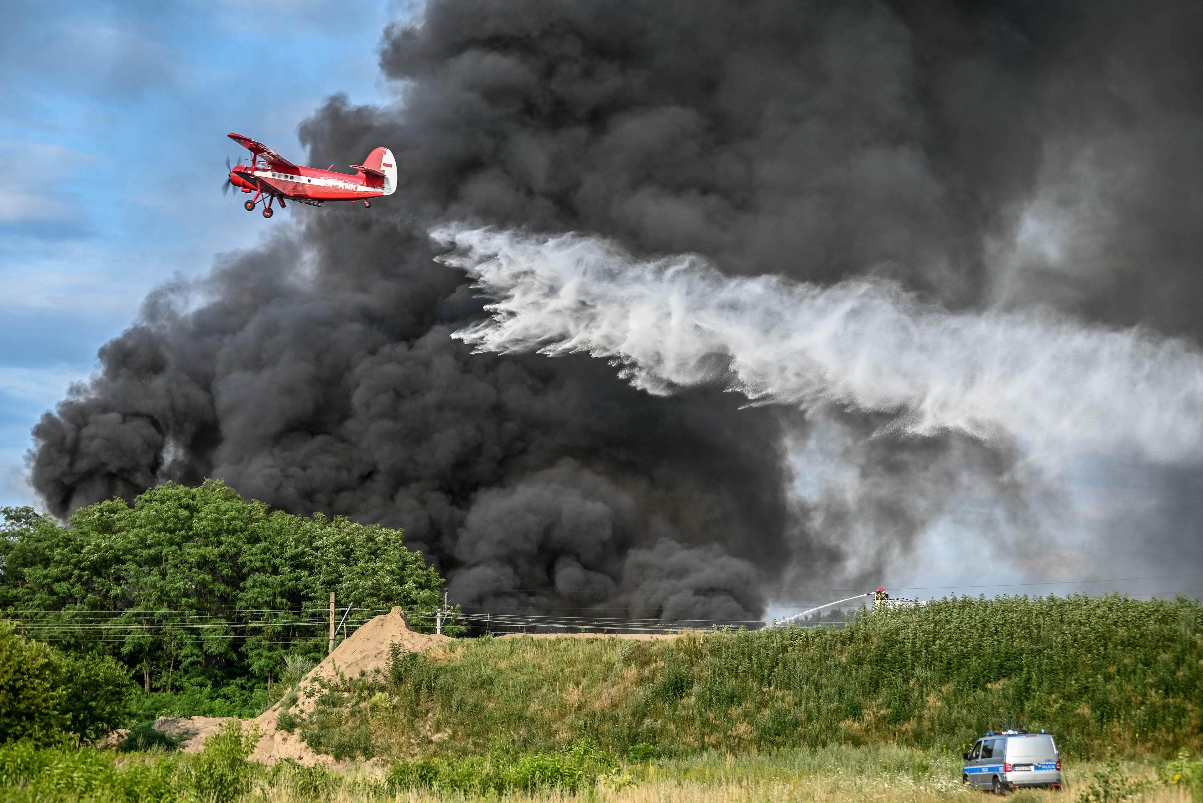 Pożar składowiska w Zielonej Górze. Samolot gaśniczy w akcji na tle gęstego czarnego dymu.