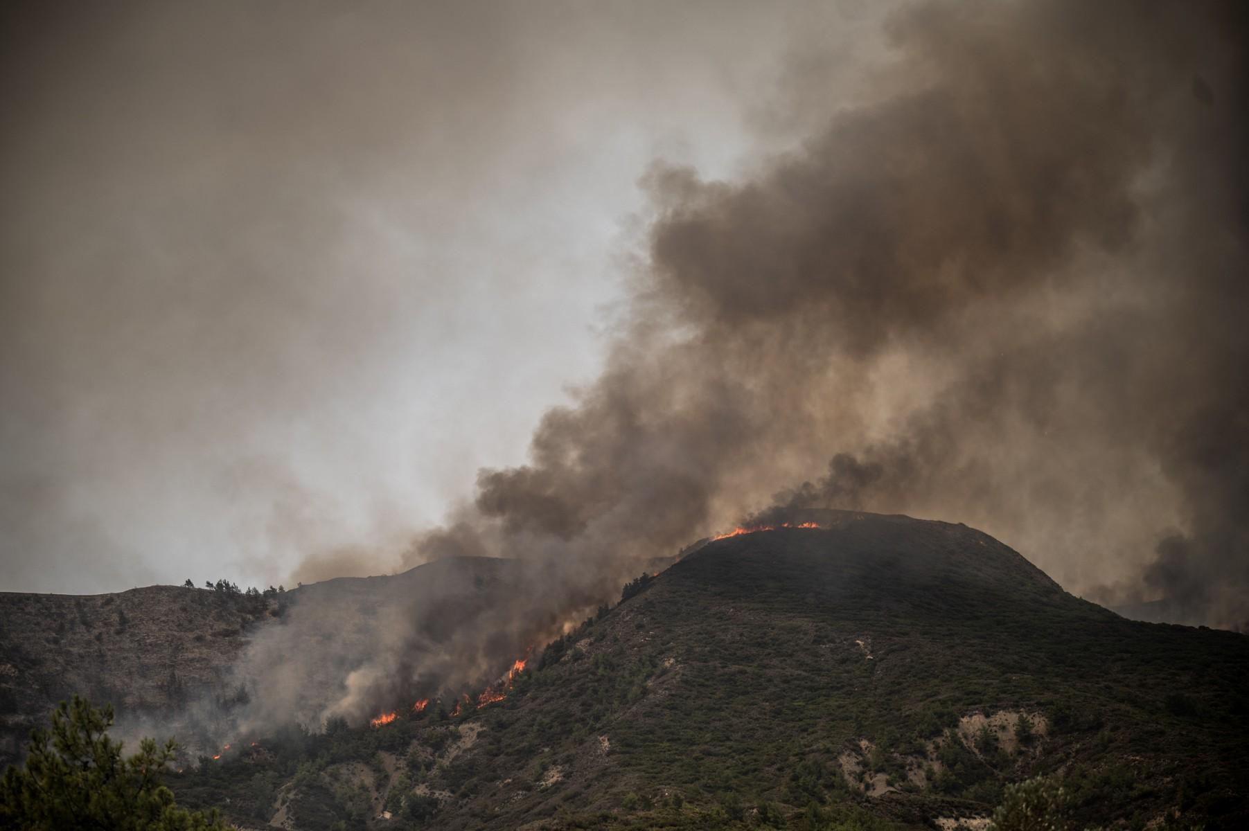 This photograph taken on July 26, 2023, shows an ongoing fire near Vati, on the Greek Aegean island of Rhodes. - Wildfires have been raging in Greece amid scorching temperatures, forcing mass evacuations in several tourist spots including on the islands of Rhodes and Corfu. (Photo by Angelos Tzortzinis / AFP)