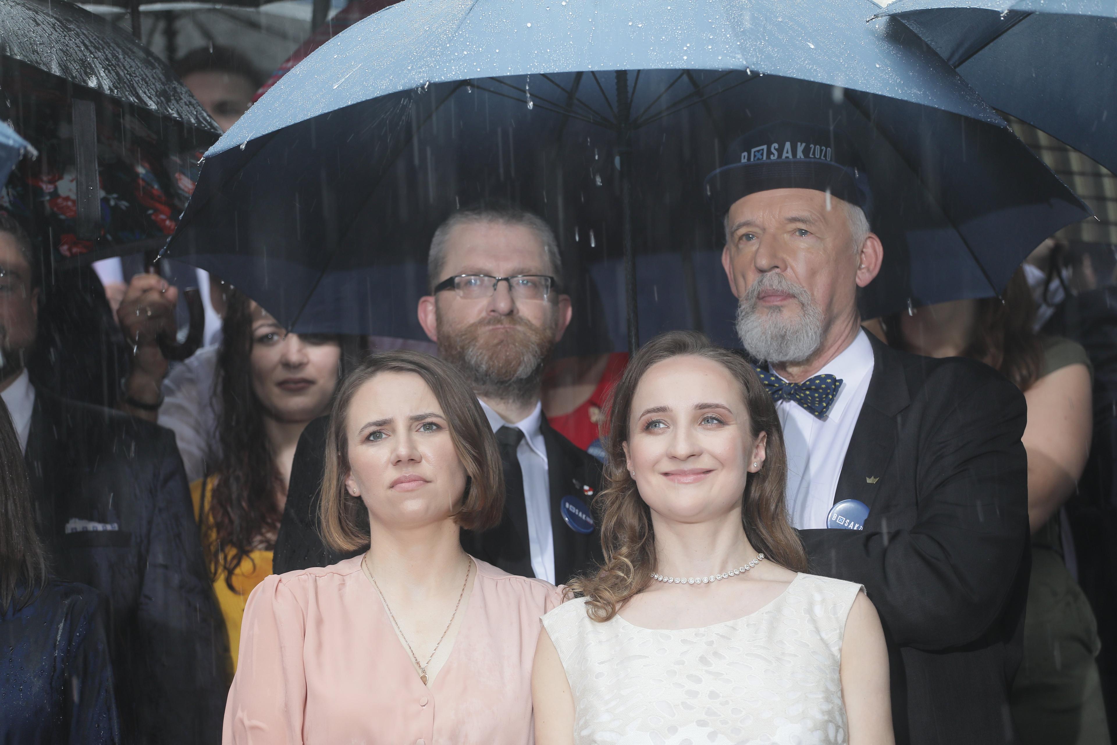 Z tyłu Grzegorz Braun i Janusz Korwin-Mikke pod parasolem, z przodu dwie kobiety, po prawej Karina Bosak