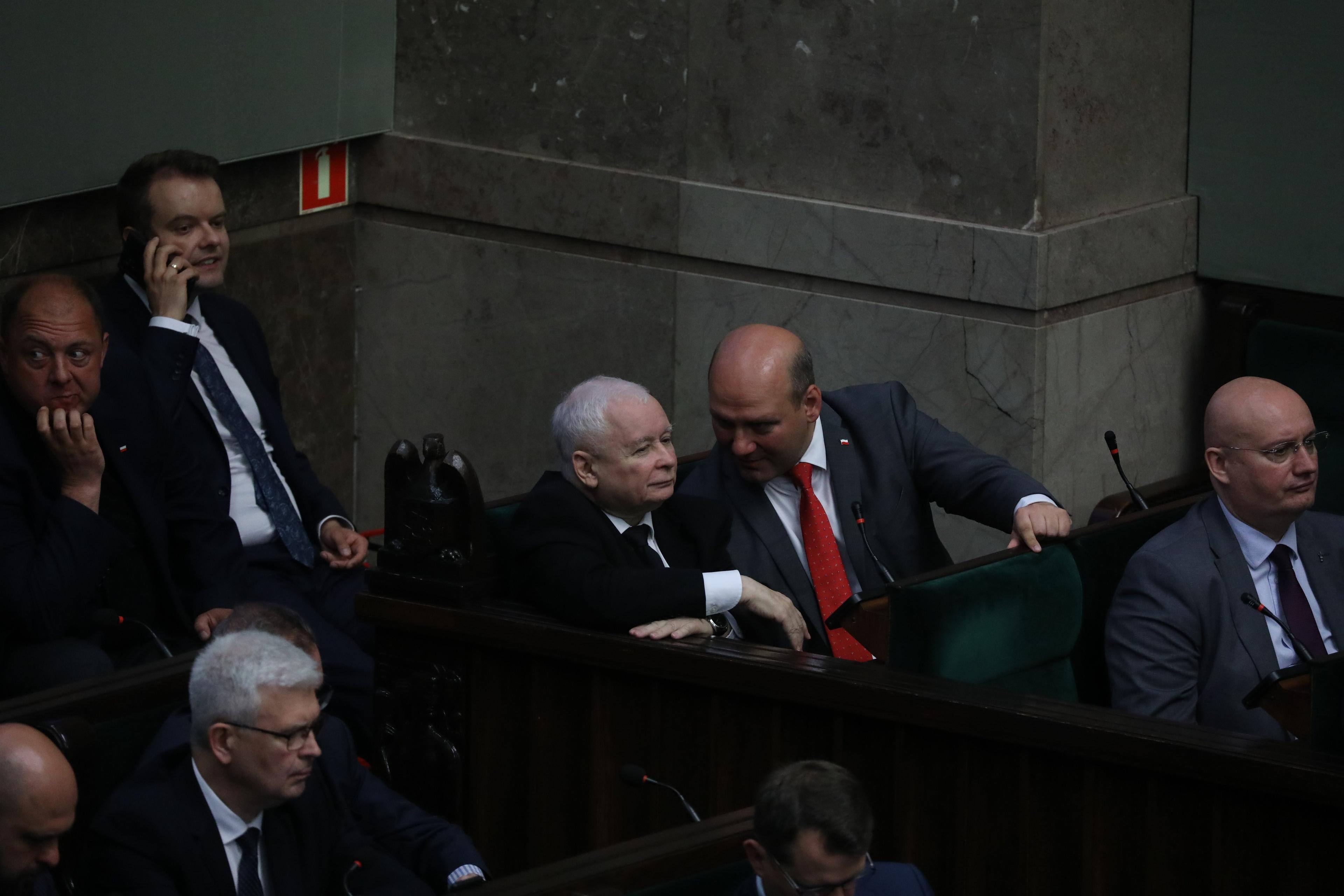Dwóch zadowolonych z siebie mężczyzn rozmawia w ławach rządowych w Sejmie