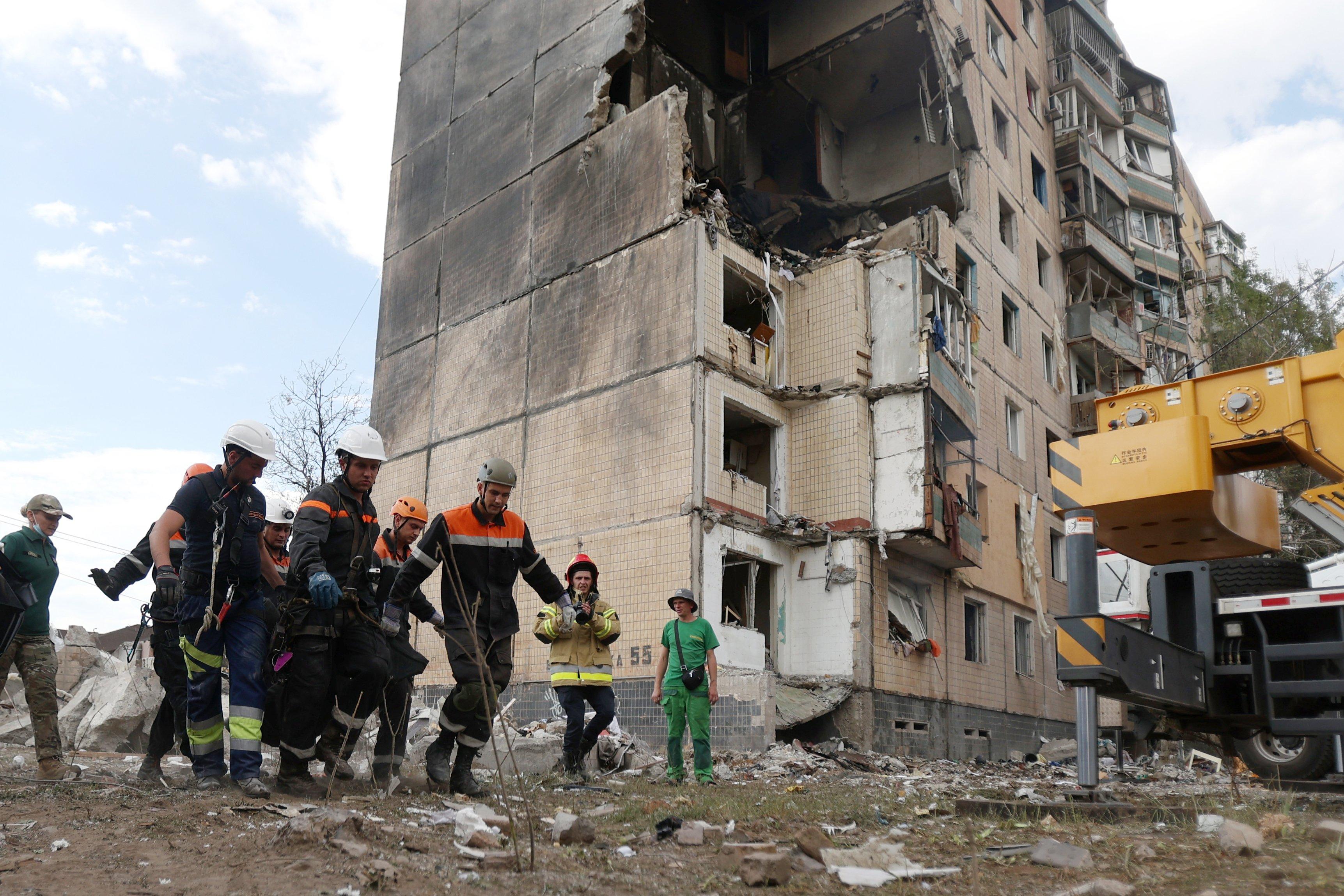 Rescuers carry the body of a resident retrieved after a nine-storey residential building was partially destroyed as a result of Russian missiles strike in Kryvyi Rig on July 31, 2023, amid the Russian invasion of Ukraine. - At least four people were killed including a 10-year-old child after a Russian missile attack on the central Ukrainian city of Kryvyi Rig, officials said. (Photo by Anatolii STEPANOV / AFP)