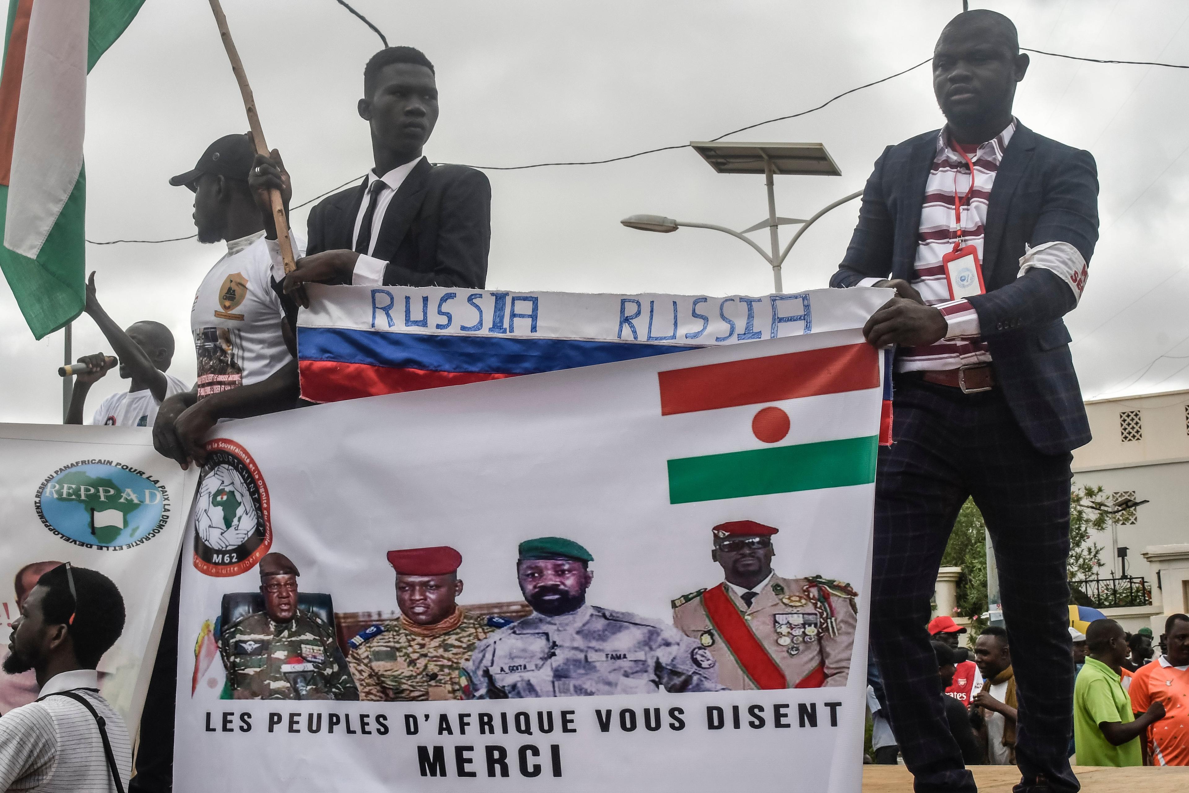 Afrykanie demonstrujący z flagami Rosji i banerem przedstawiającym wojskowych