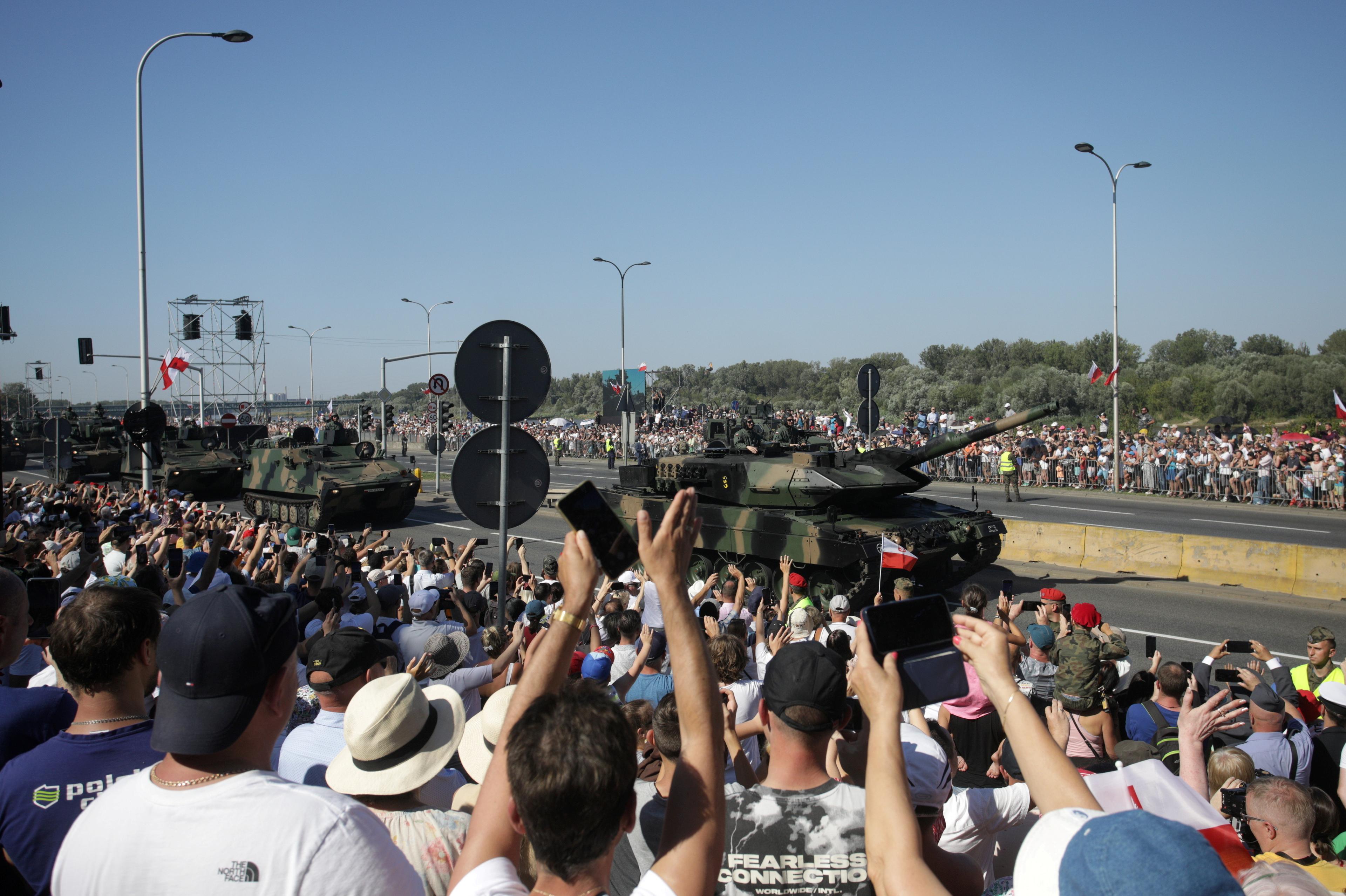 tłum osób obserwuje przejeżdżające czołgi