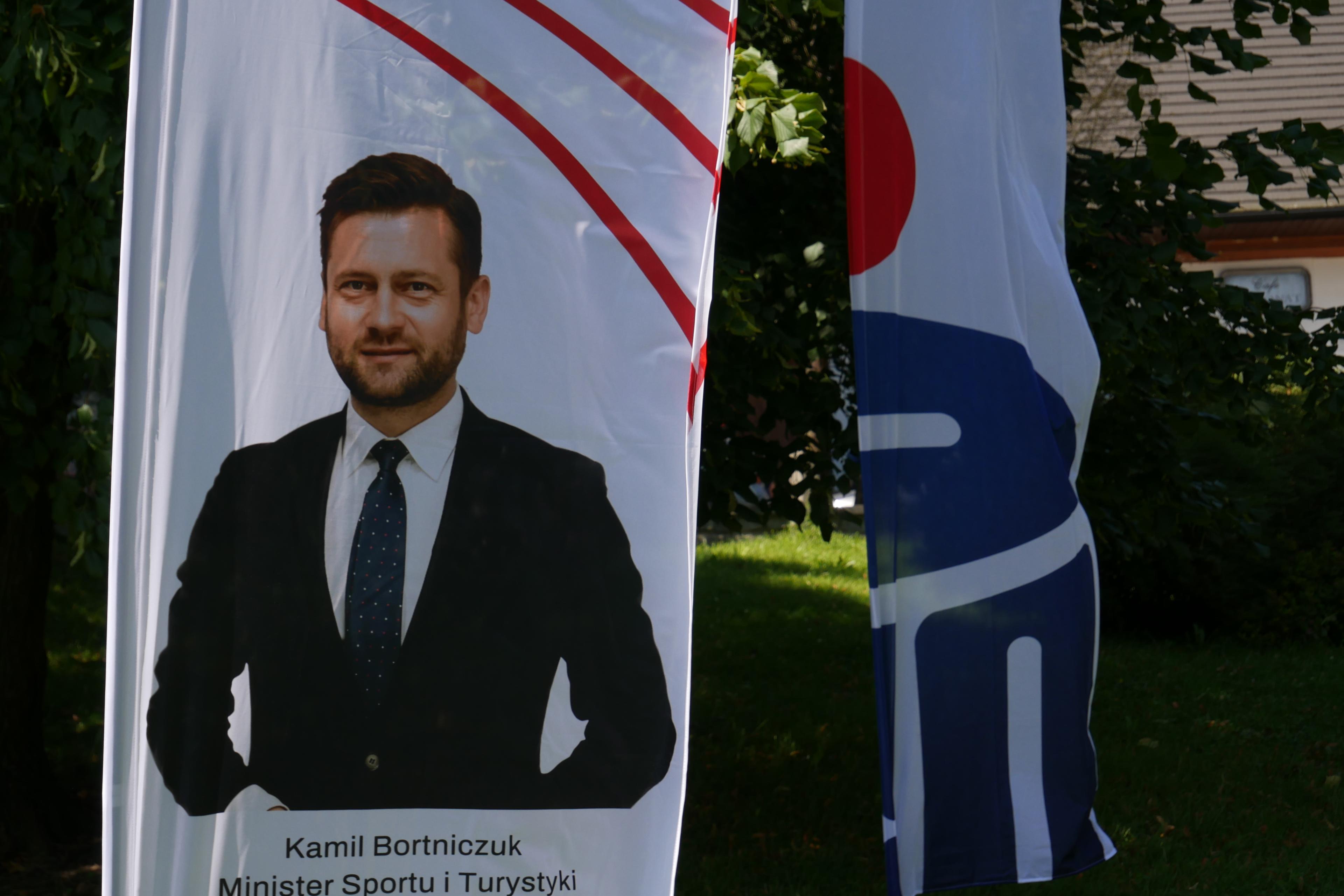 plakat z mężczyzną w garniturze i podpisem "Kamil Bortniczuk"