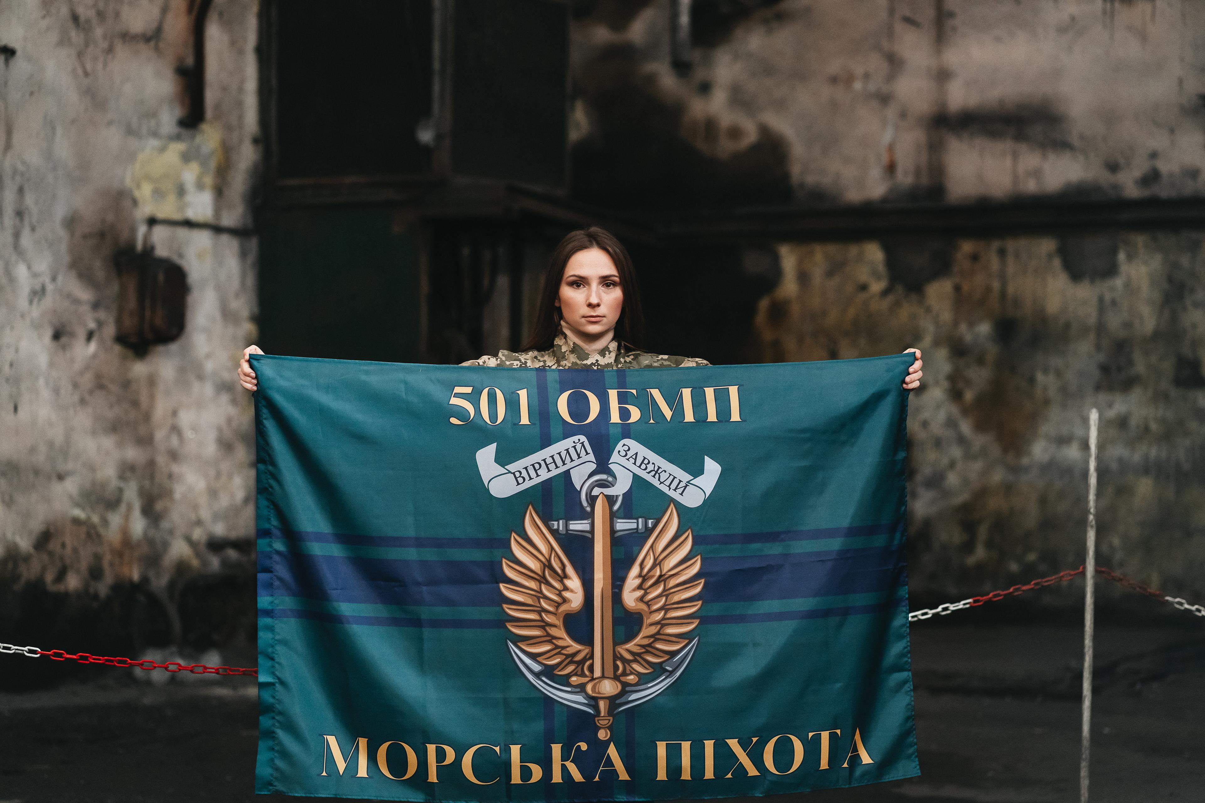 Ciemnowłosa dziewczyna z proporcem oddziału ukraińskiej piechoty morskiej