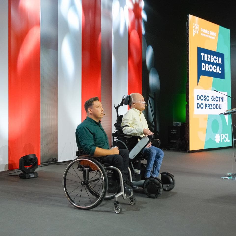 Dwaj męzczyźni na wózkach inwalidzkich prowadzą prezentację pod hasłem Trzecia Droga