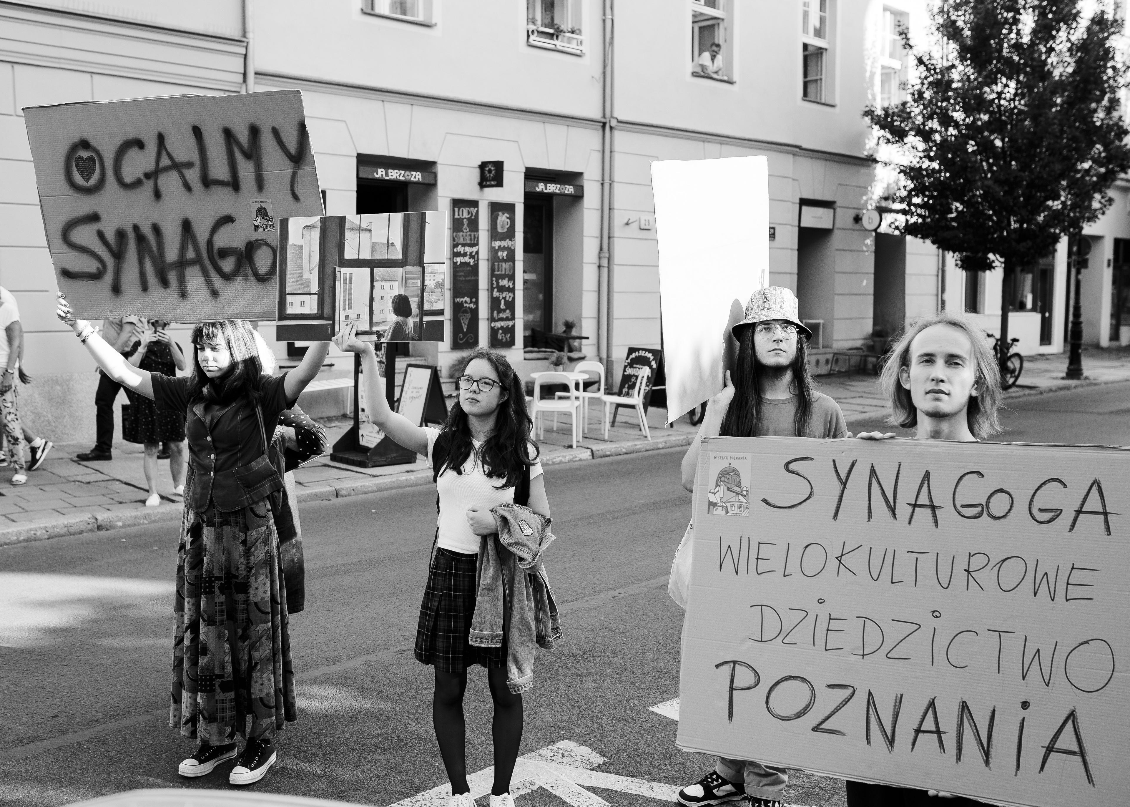 manifestacja uliczna, młodzi ludzie idą z hasłami" Synagoga wielokulturowe dziedzictwo Poznania"