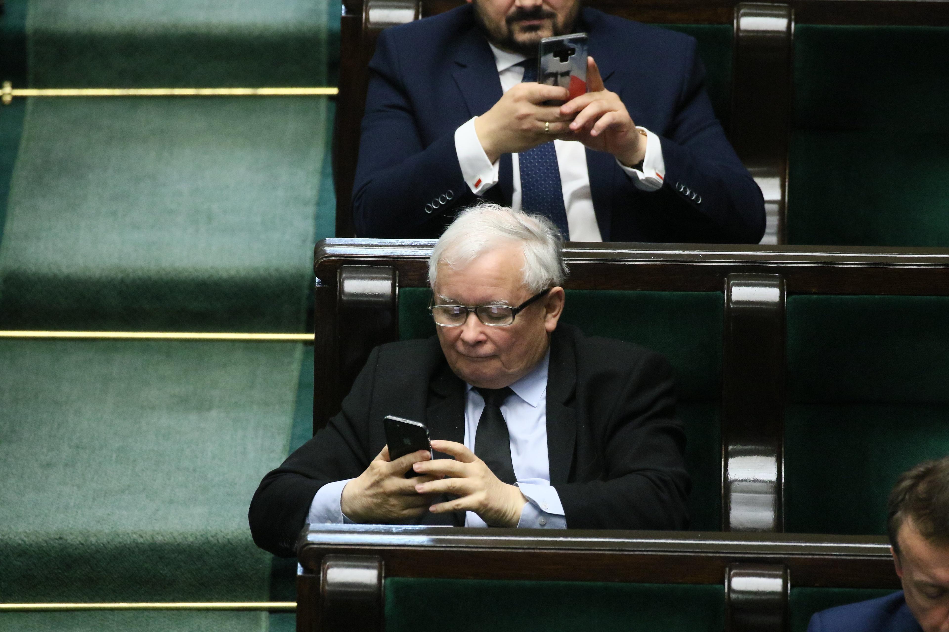 Jarosław kaczyński w ławie sejmowej odczytuje wiadomość w telefonie