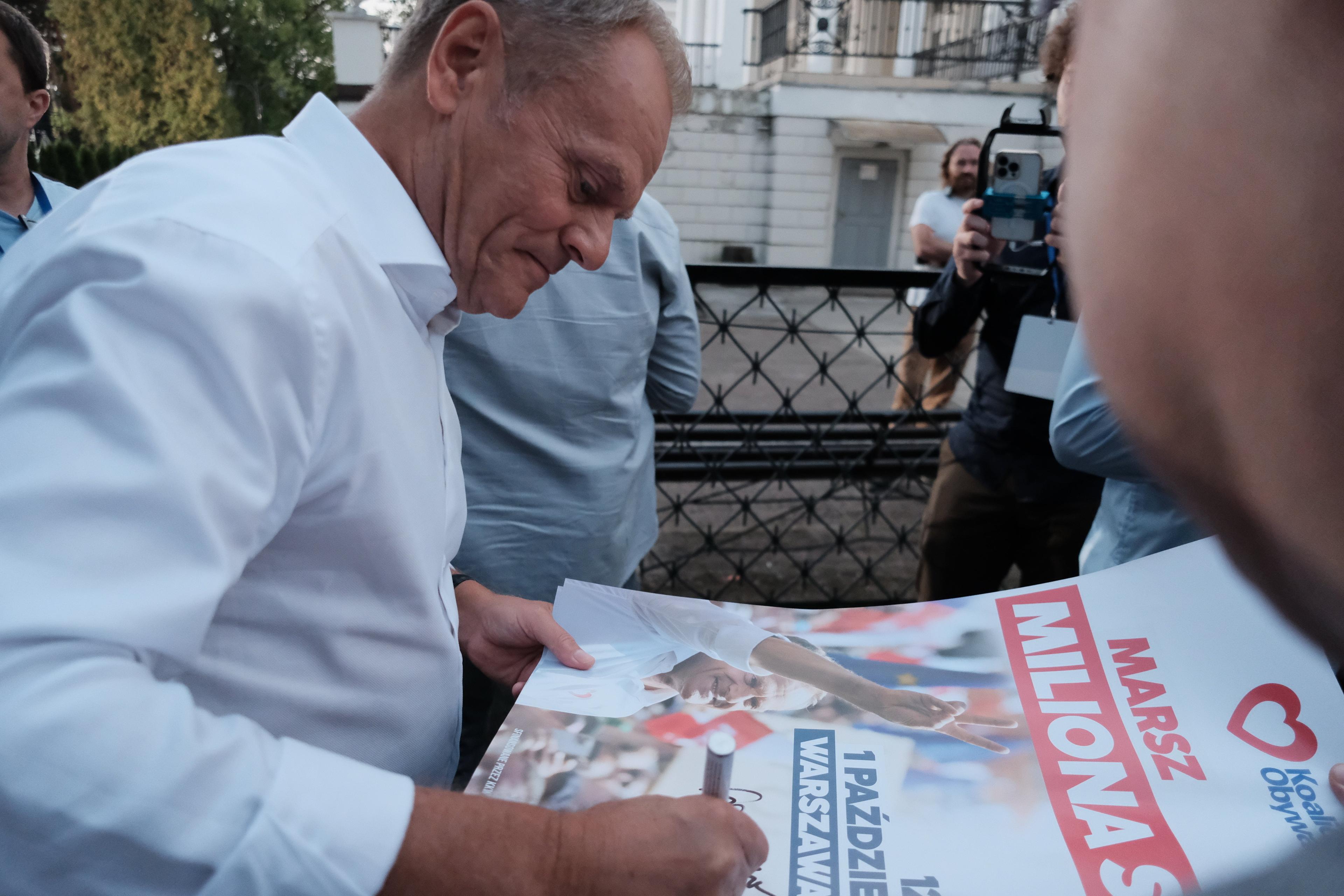 Na zdjęciu lider KO Donald Tusk podpisujący plakat
