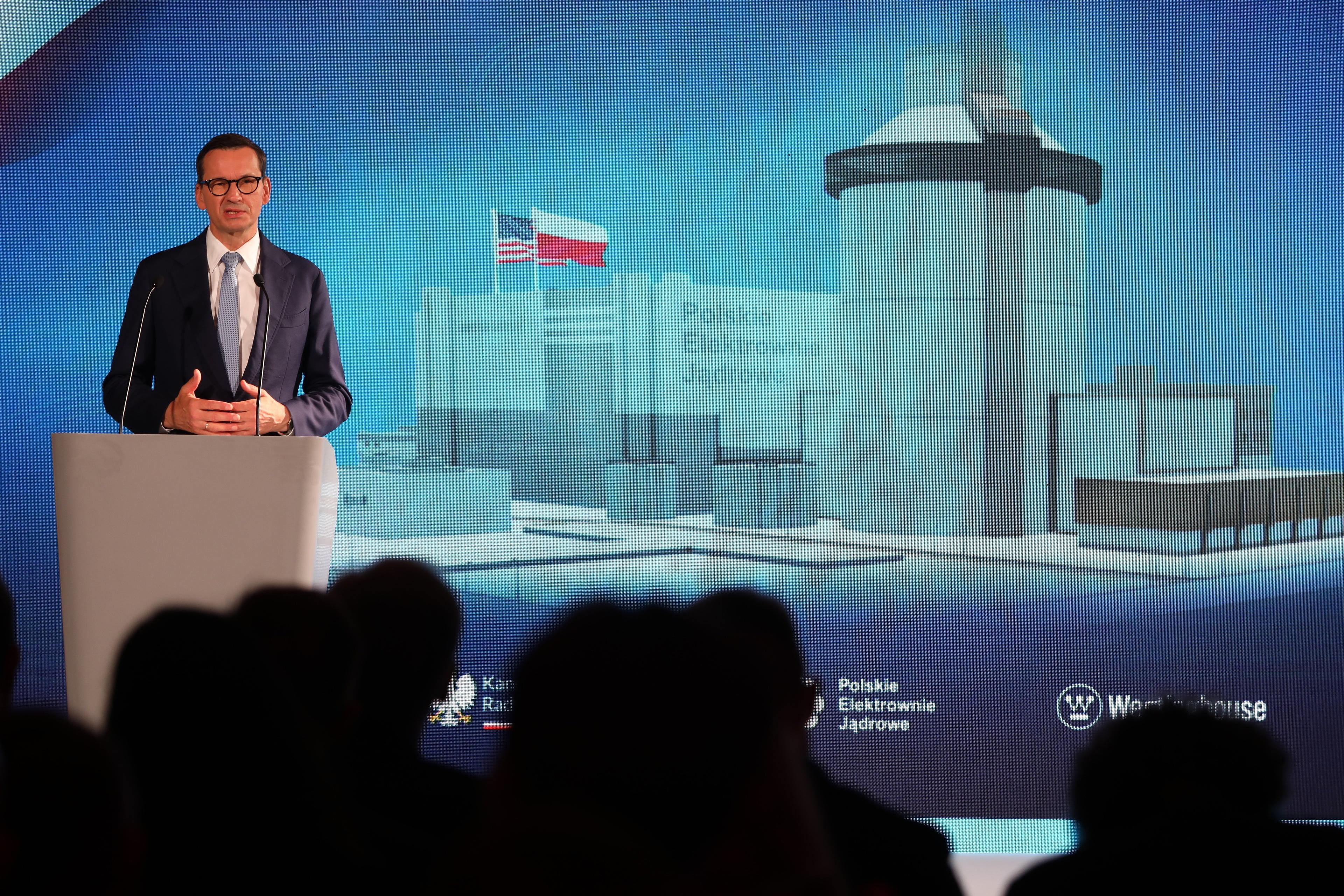 premier Mateusz Morawiecki na tle wizualizacji przedstawiającej elektrownię atomową