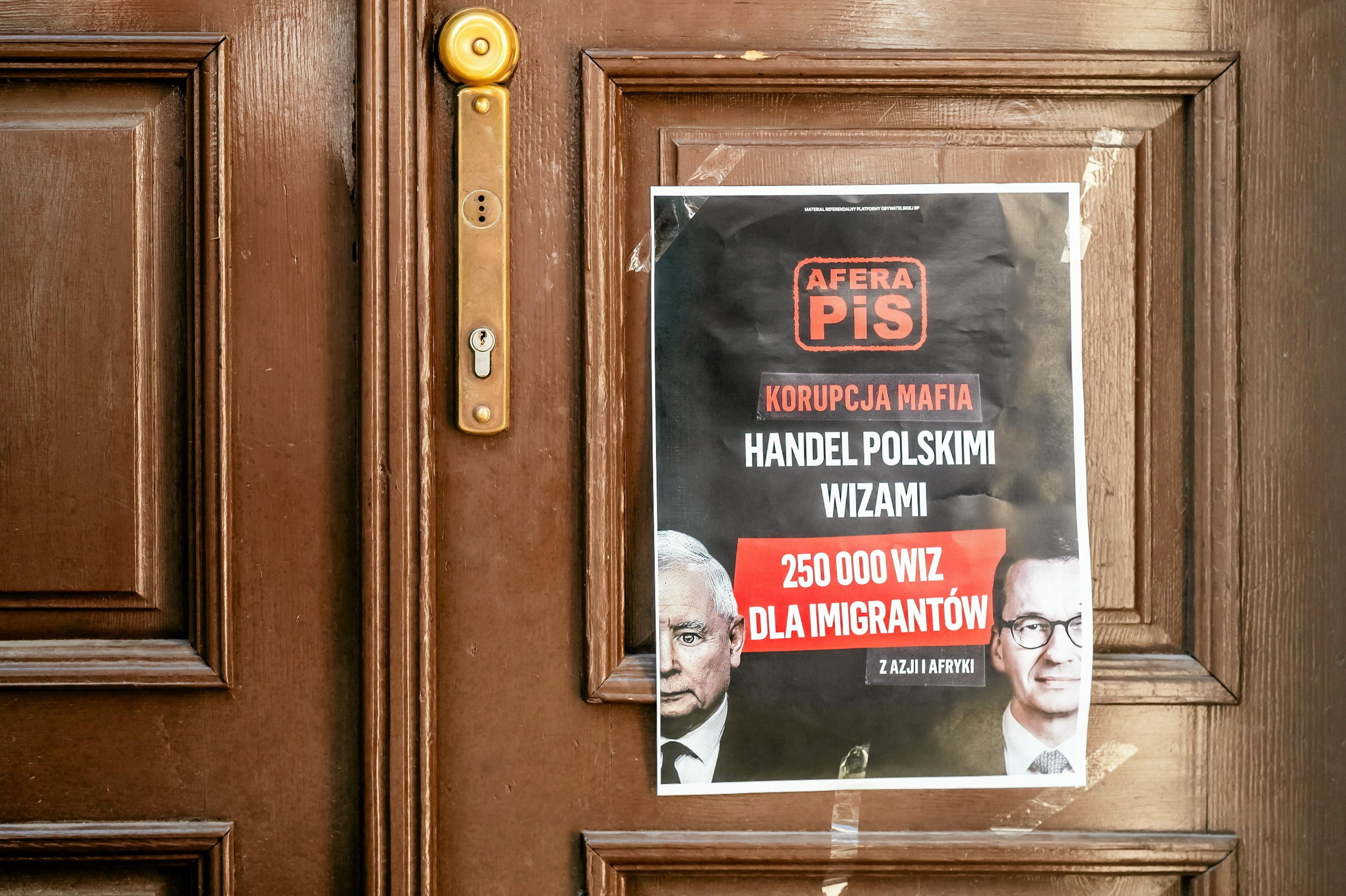 Plakat powieszony na drzwiach siedziby PIS "Afera pis. Korupcja mafia. Handel polskimi wizami. 250 000 wiz dla imigrantów z Afryki i Azji" .