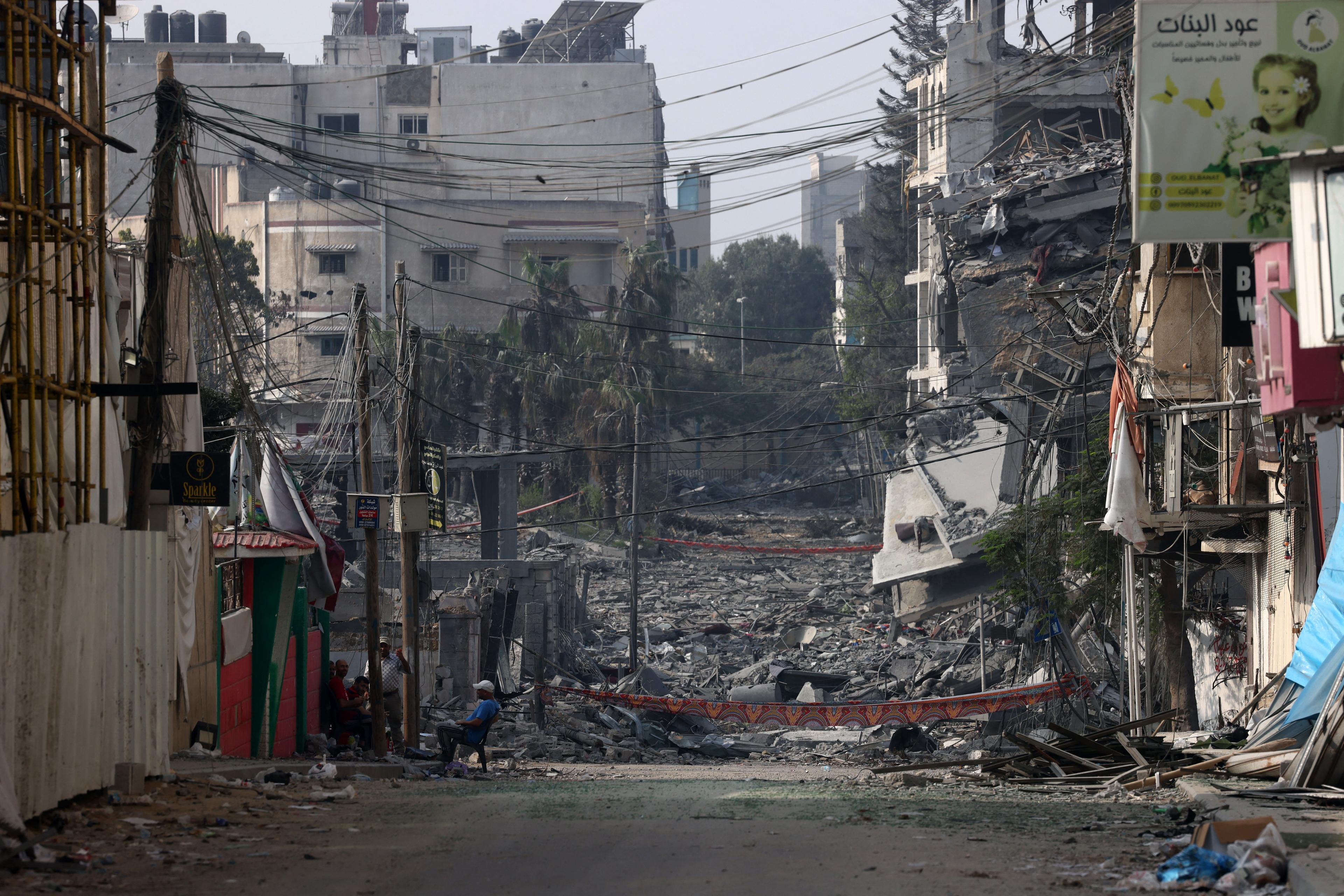 ulica ze zburzonymi budynkami, mężczyzna siedzi na krześle i patrzy na ruiny