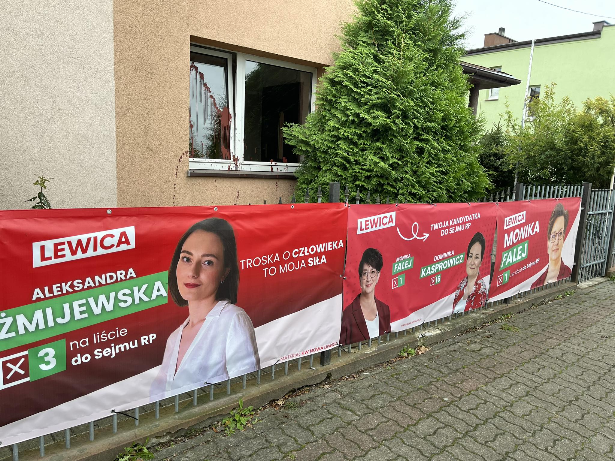 Płot przy domu, na którym wiszą czerwone banery kilku kandydatek Lewicy do Sejmu