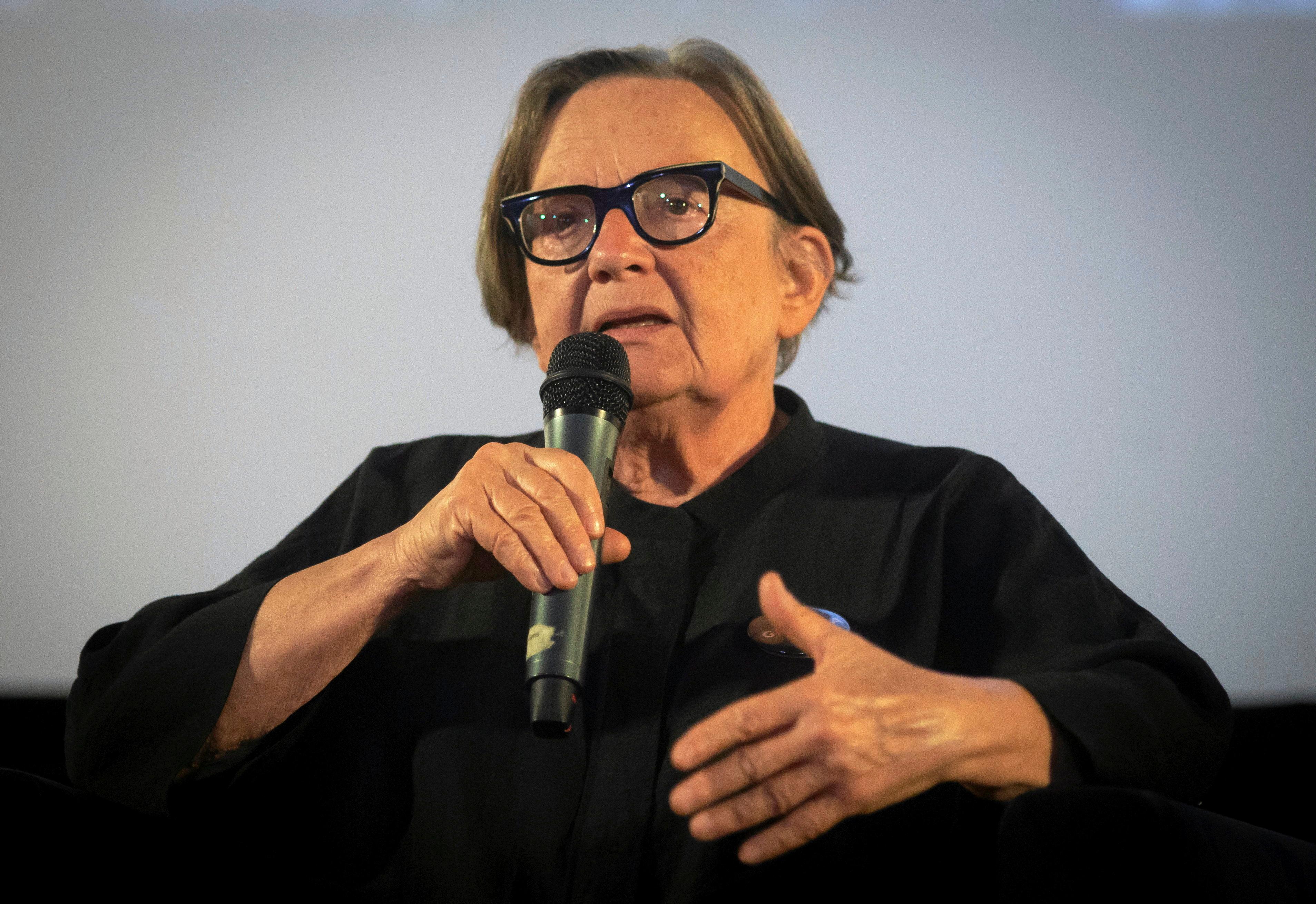 Agnieszka Holland siedzi na fotelu ubrana w czarną koszulę i przemawia do mikrofonu