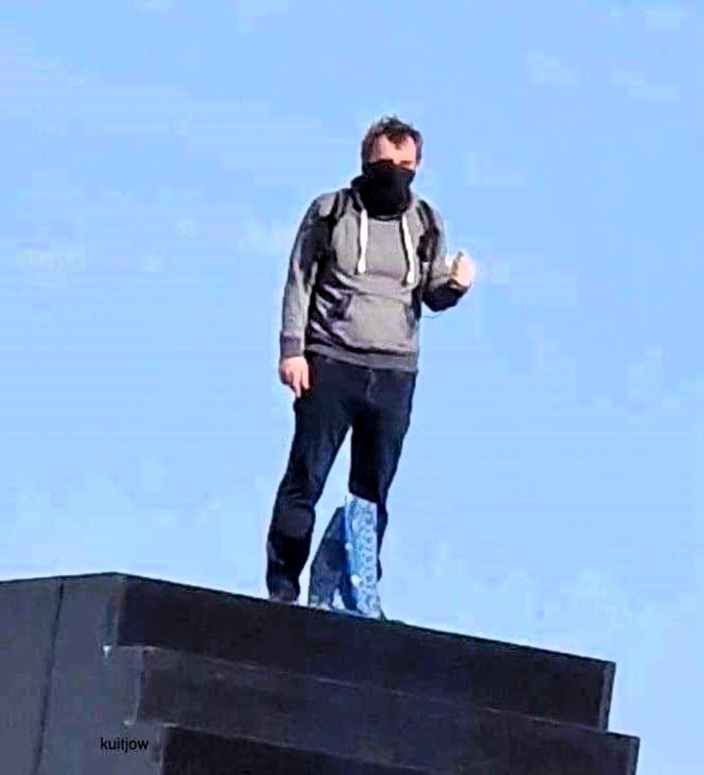Mężczyzna w masce stoi na pomniku smoleńskim
