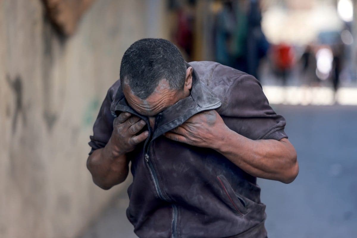 A Palestinian man wipes his eyes from dust at the scene of a strike at the Nuseirat refugee camp in the central Gaza Strip on November 4, 2023, amid ongoing battles between Israel and the militant group Hamas. (Photo by MOHAMMED ABED / AFP)