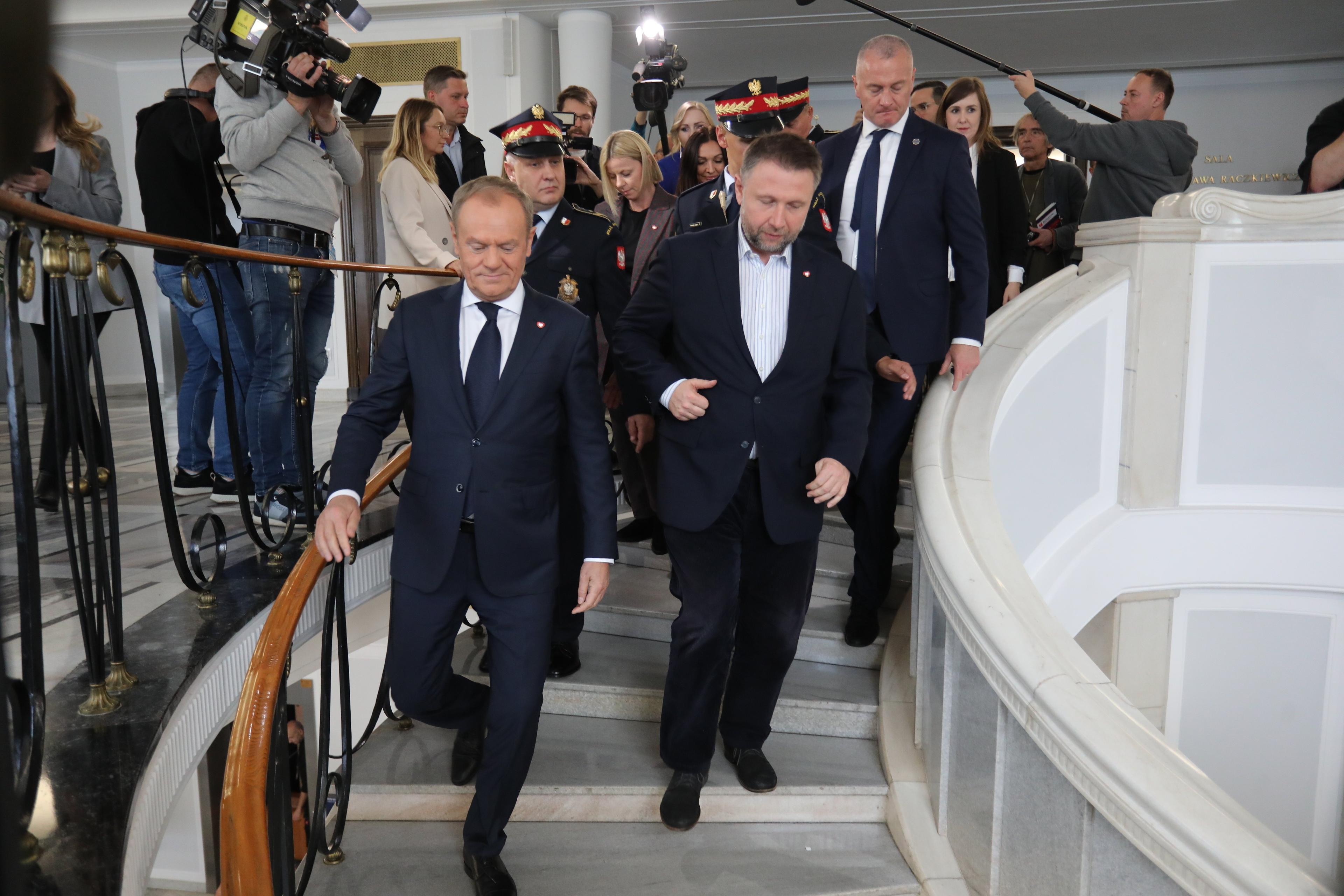 Donald Tusk i Marcin Kierwiński schodzą po schodach w Sejmie w otoczeniu dziennikarzy