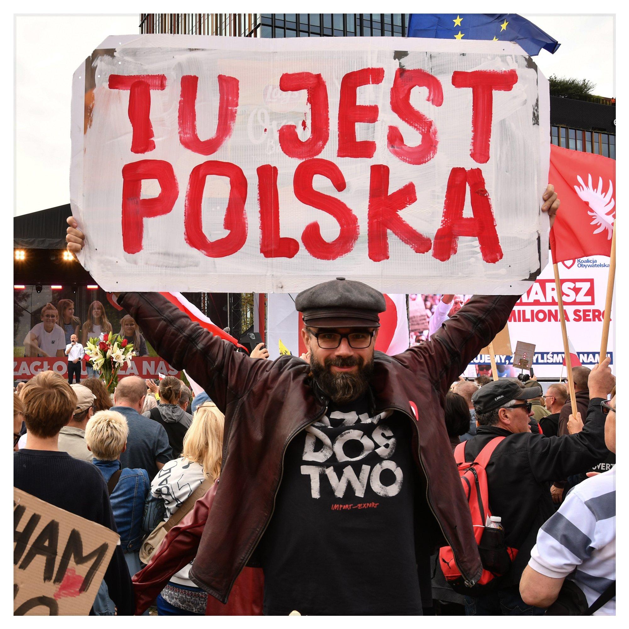 Brodaty mężczyzna z transparentem "Tu jest Polska"