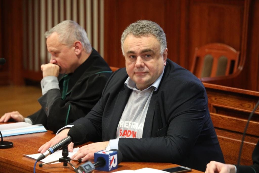 Dwaj mężczyźni siedzą za stołem w sali sądowej, jeden z nich to Tomasz Sakiewicz