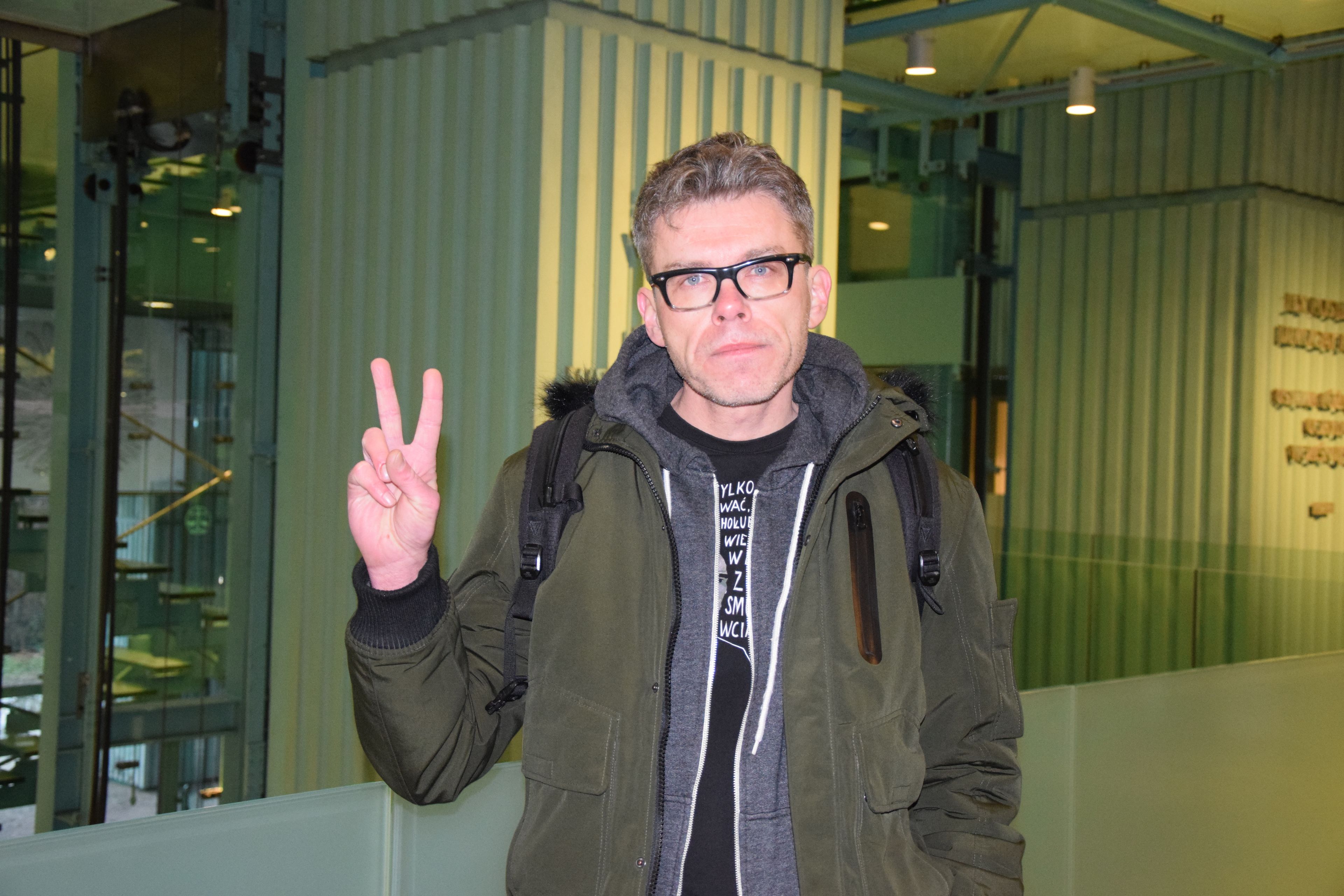 Mężczyzna w okularach pokazujący znak V