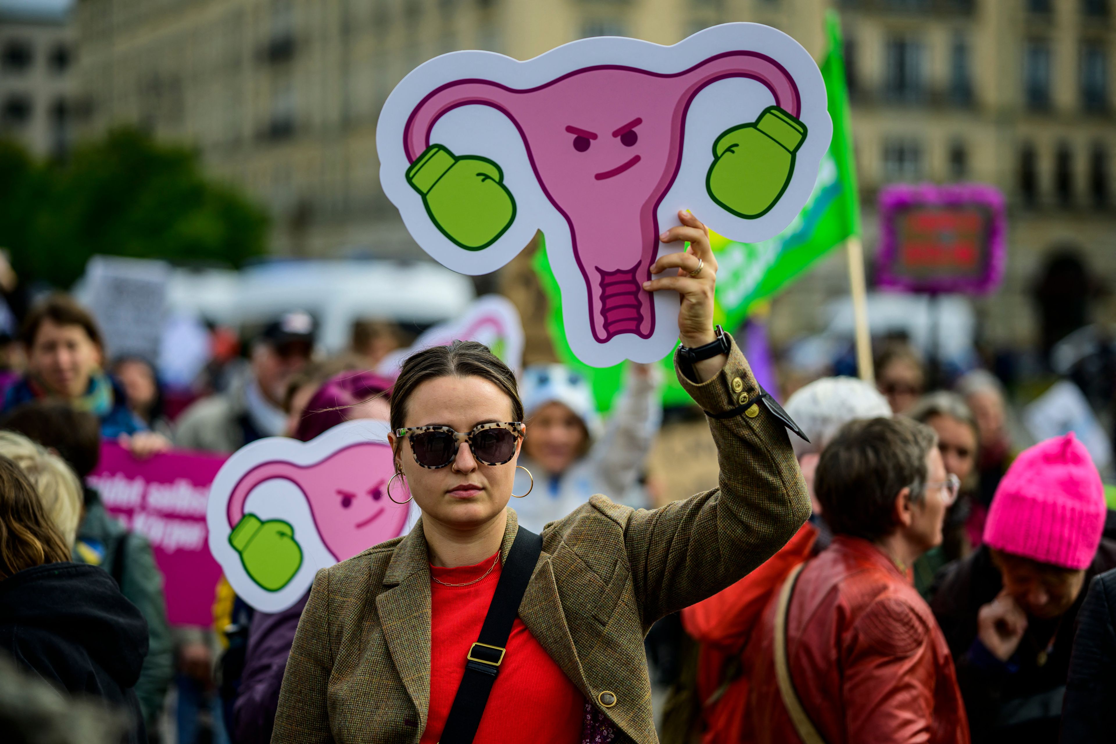 Kobieta z transparentem z macicą i jajnikami - na jajniki naciągnięte rękawice bokserskie