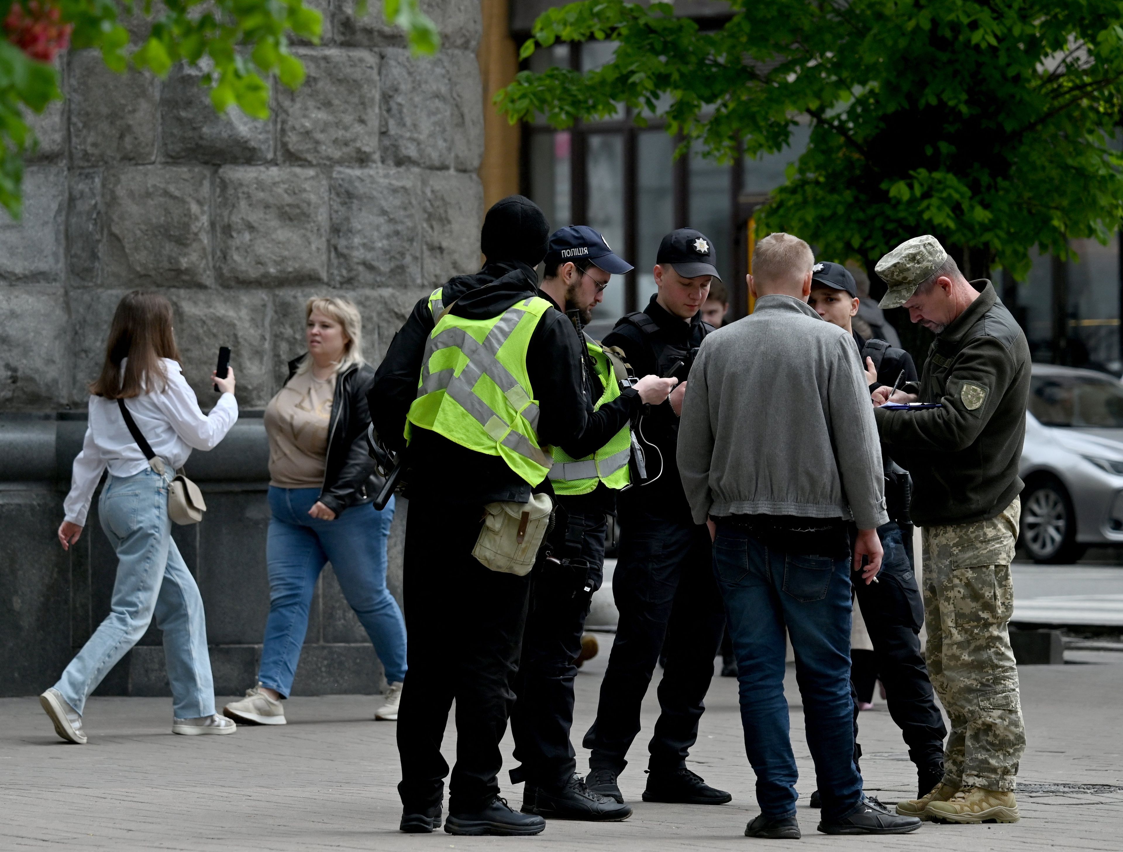 grupa mężczyzn otoczona na ulicy przez żołnierzy, którzy sprawdzają ich dokumenty. Mobilizacja w Ukrainie
