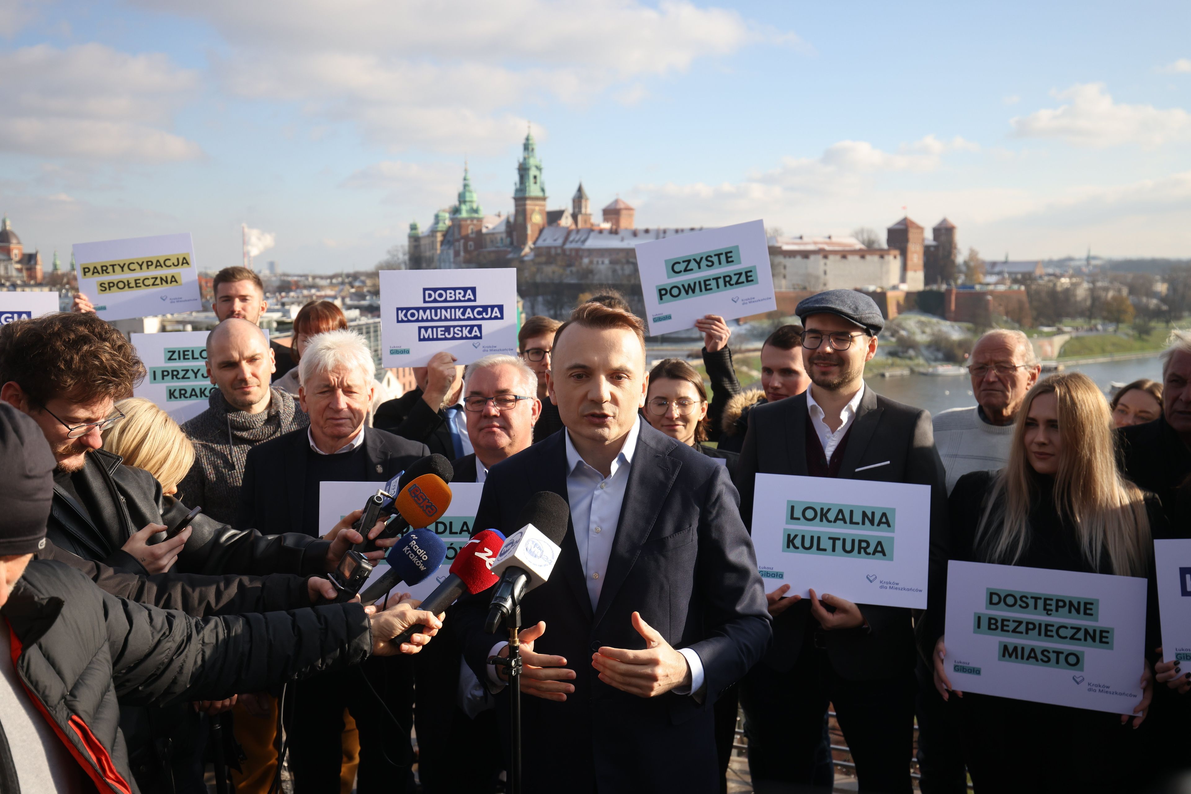 Łukasz Gibała stoi na tle Wawelu, z nim członkowie jego sztabu