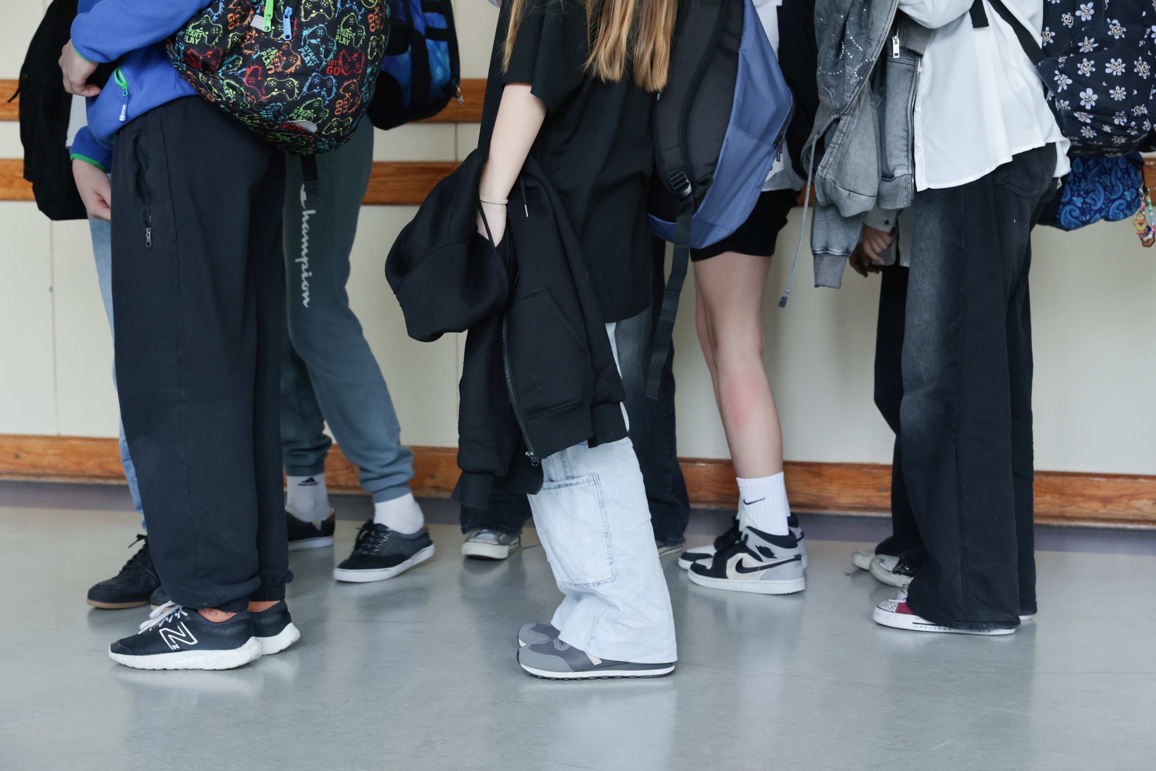 Uczniowie i uczennice na korytarzu szkoły. Prace domowe