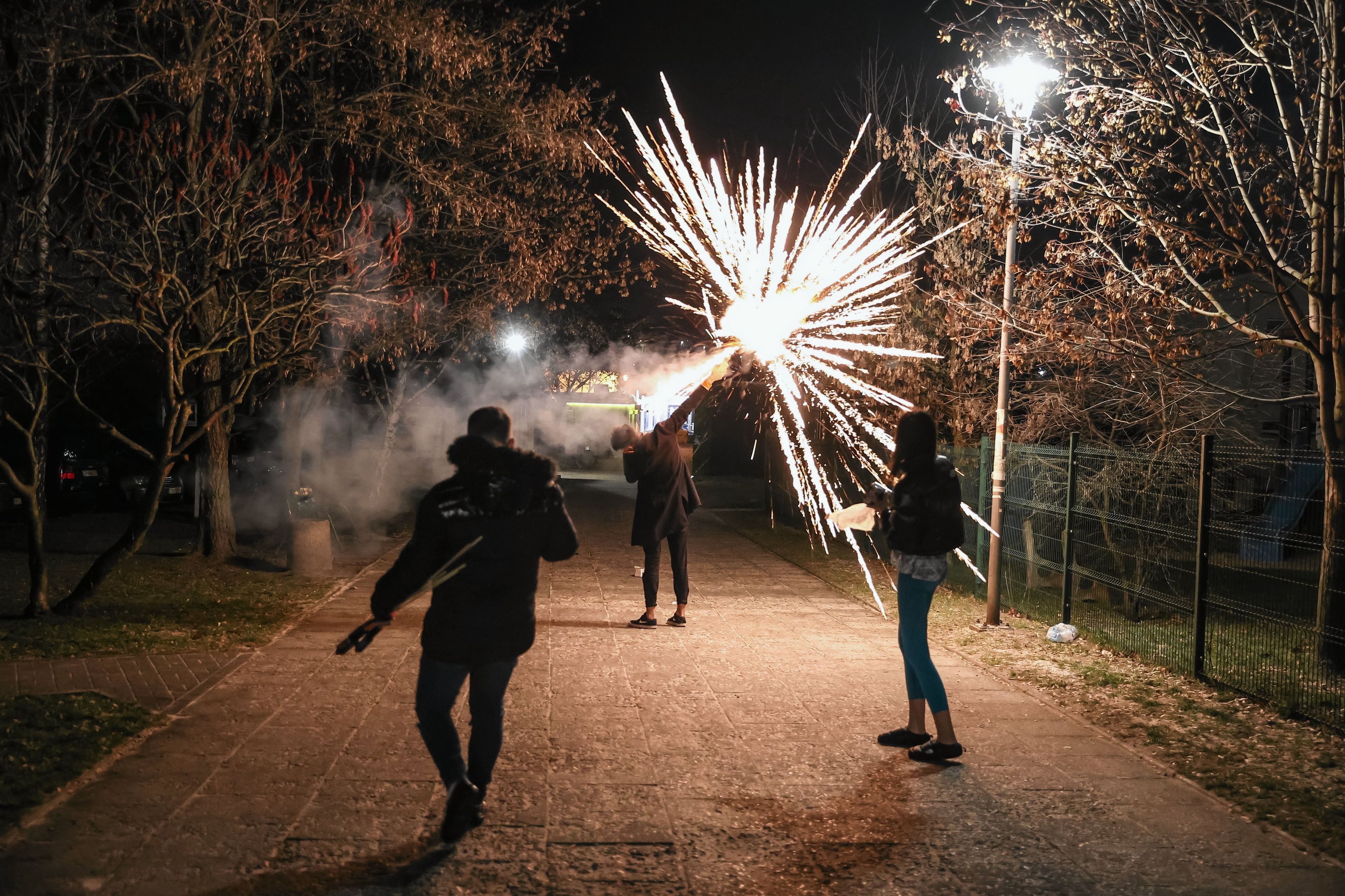 trzy osoby odpajaką fajerwerki