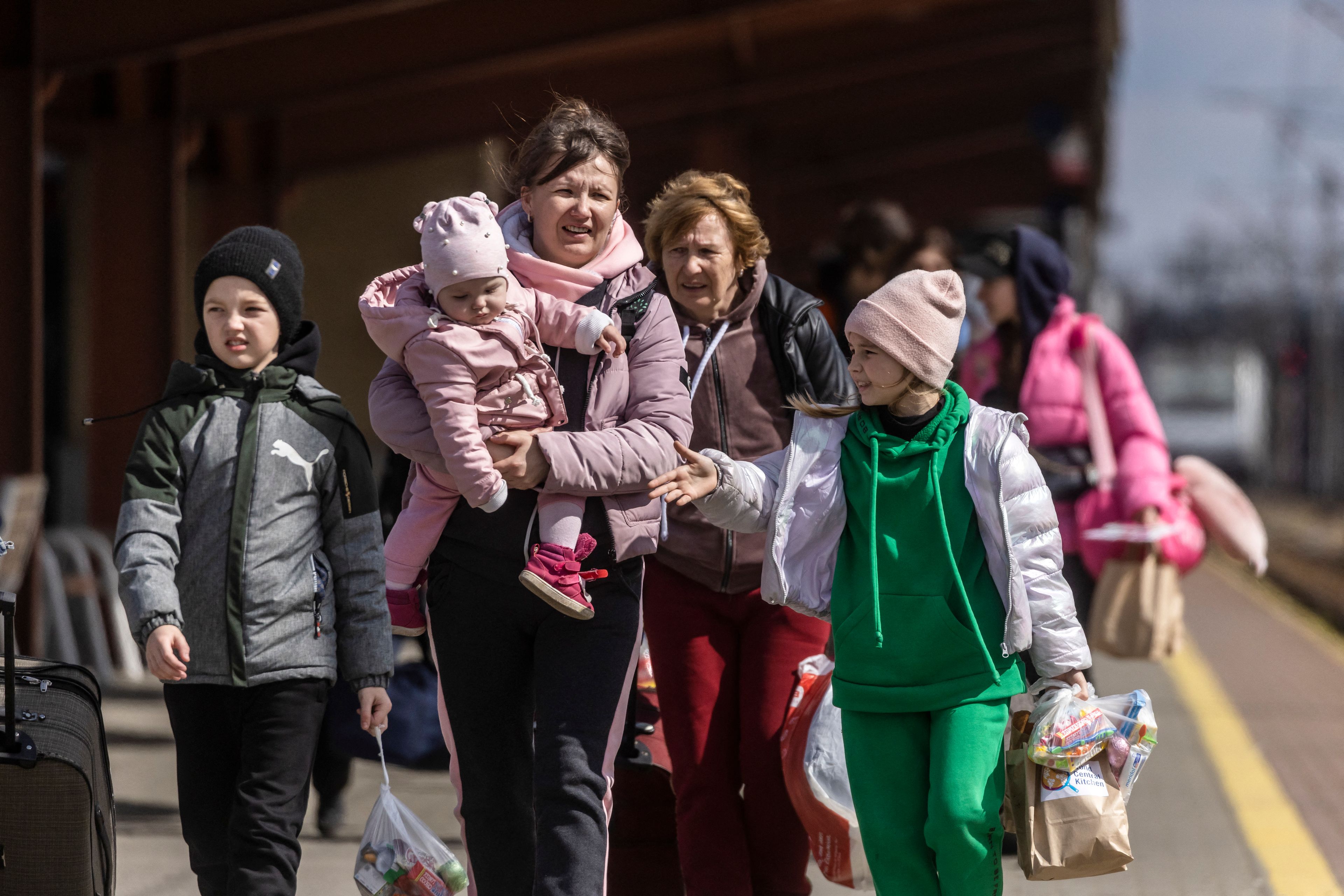 Na zdjęciu dwie kobiety i trójka dzieci. Młodsza kobieta trzyma na rękach małe dziecko.