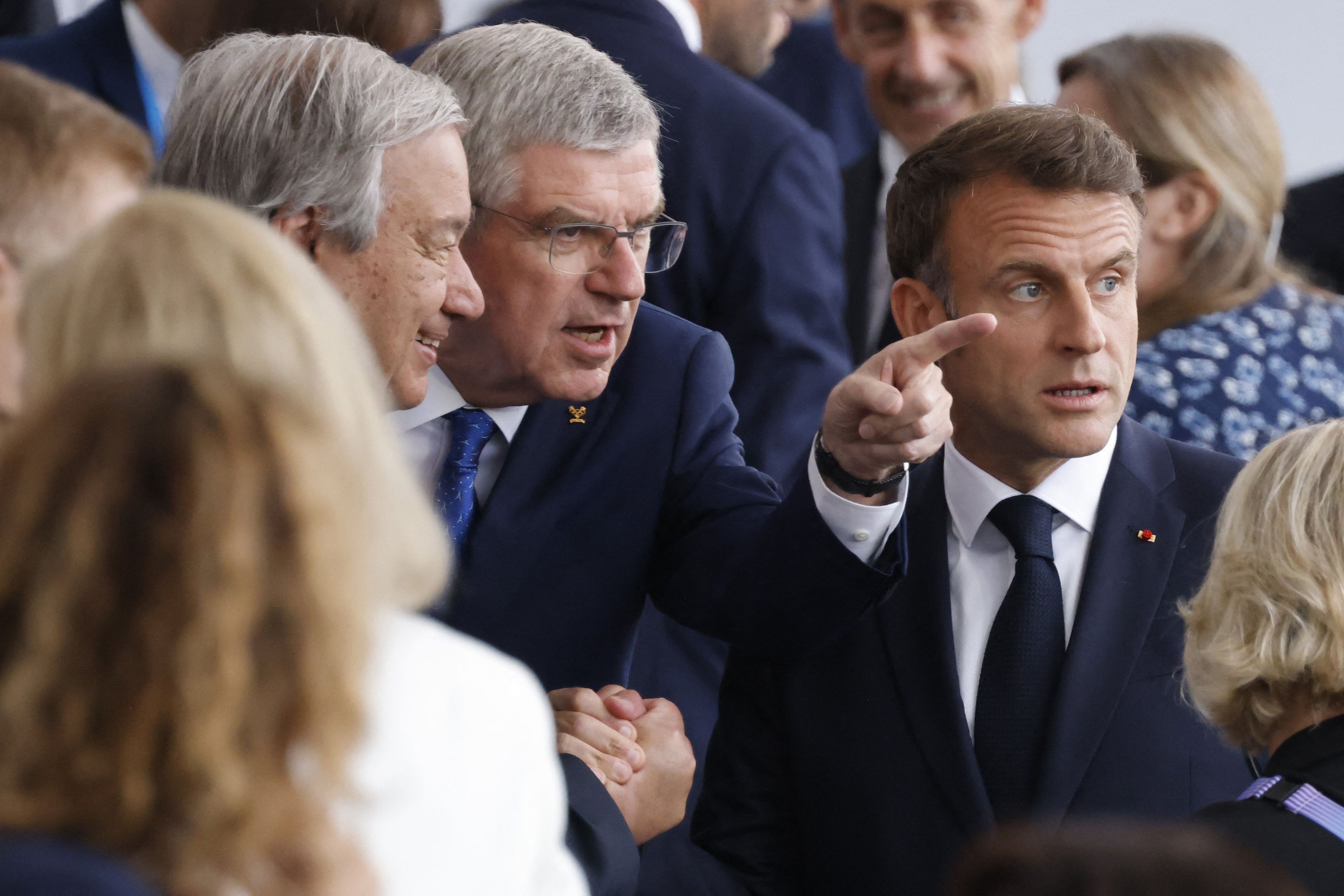 The Secretary-General of the United Nations (UN) Antonio Guterres (C), the President of the International Olympic Committee (IOC) Thomas Bach (C) and French president Emmanuel Macron talk as they arrive to attend the opening ceremony of the Paris 2024 Olympic Games in Paris on July 26, 2024. (Photo by Ludovic MARIN / POOL / AFP)
