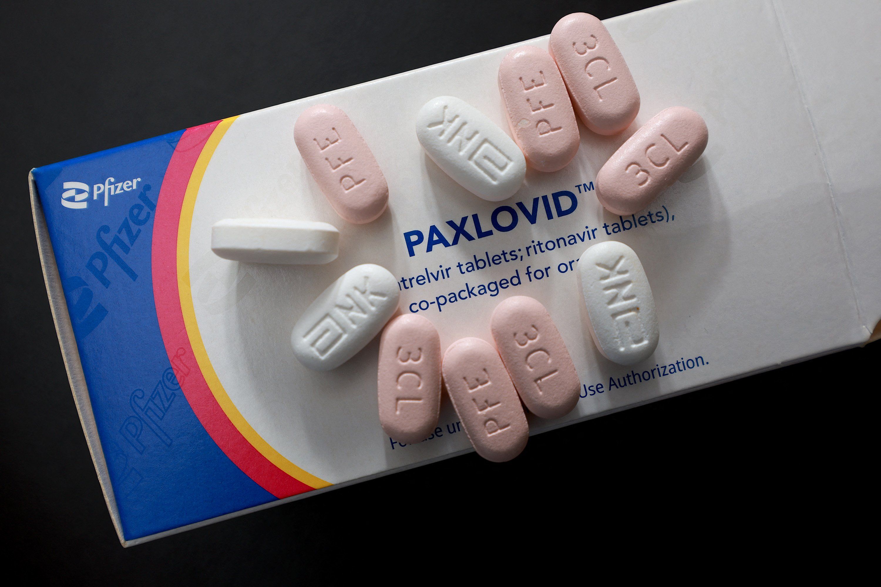 Opakowanie leku Paxlovid, na nim białe i różowe tabletki