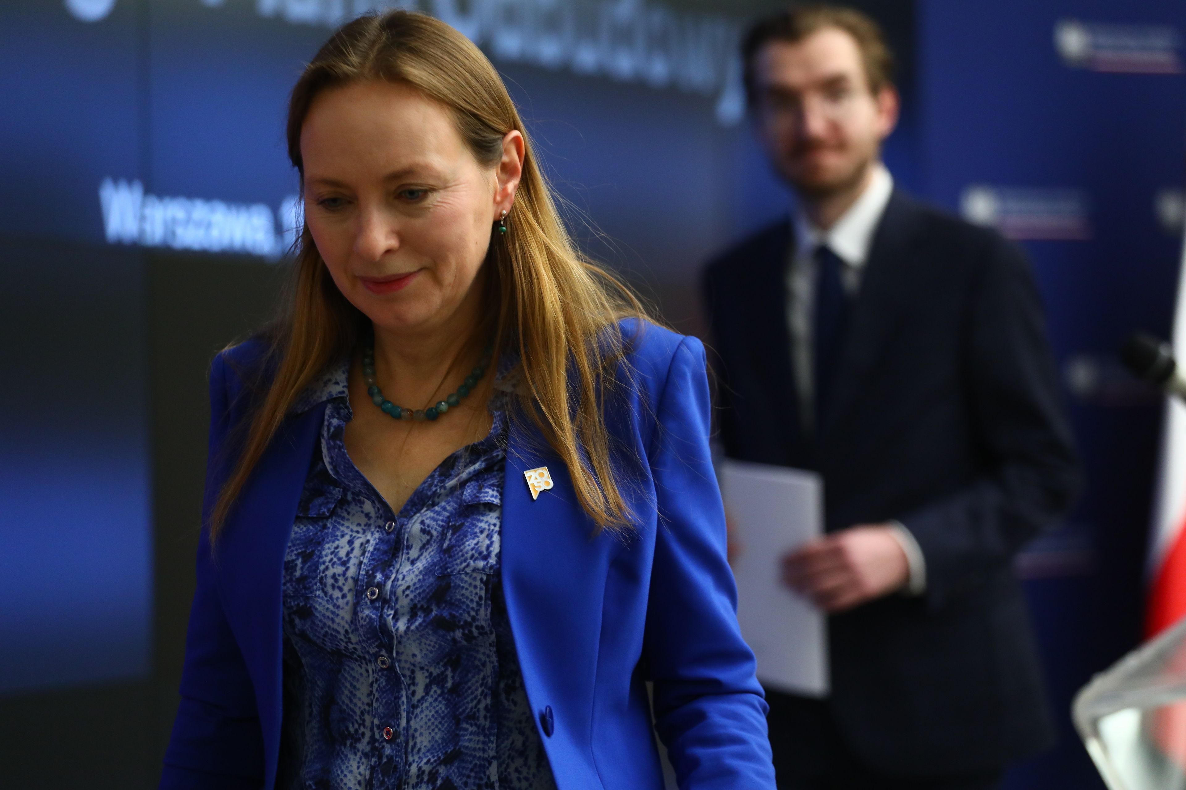Kobieta z pochyloną głową w niebieskiej marynarce, za nią mężczyzna z kartką w ręku. Katarzyna Pełczyńska-Nałęcz i Jan Szyszko