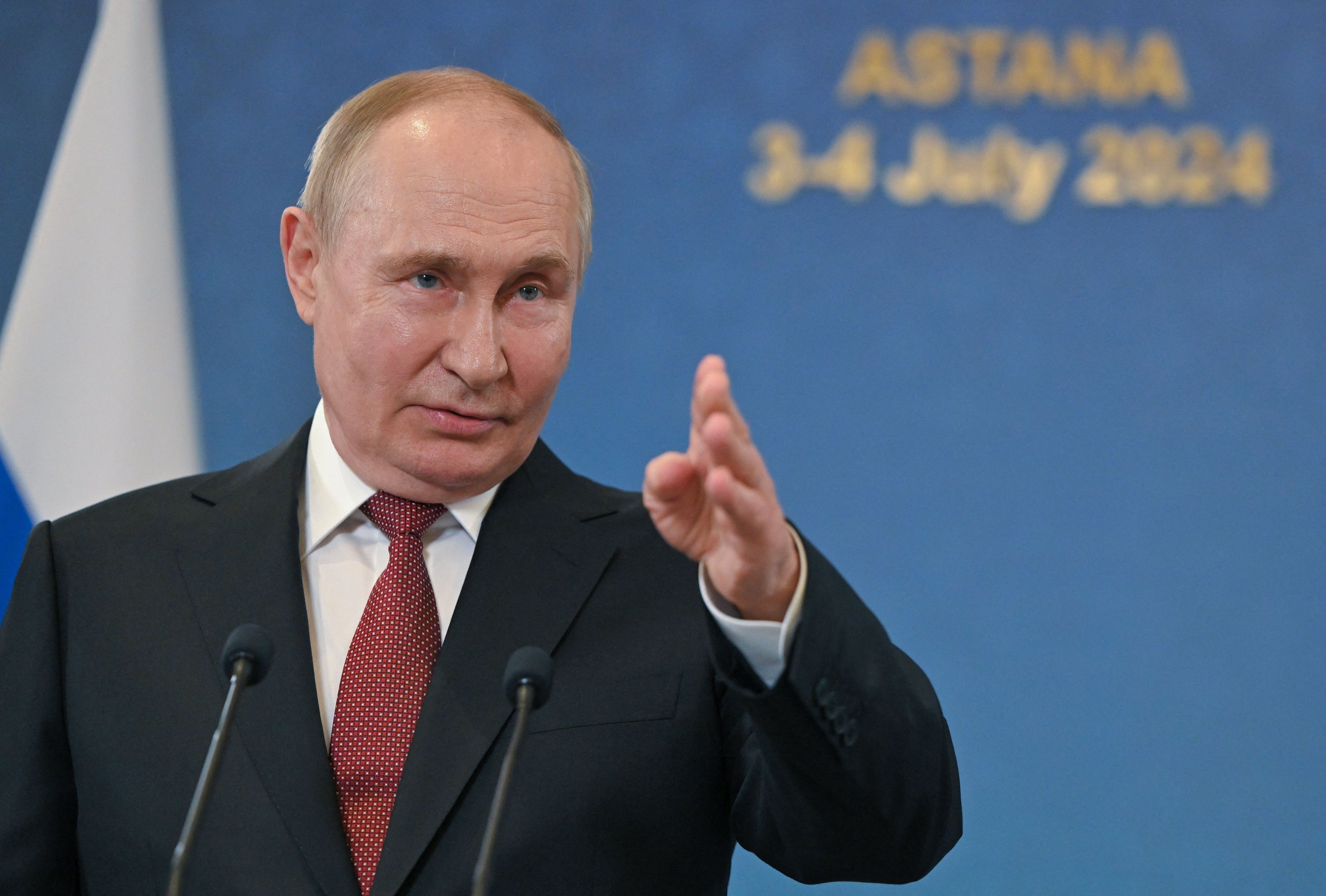 Mężczyzna - Putin - stoi z wyciągniętą ręką