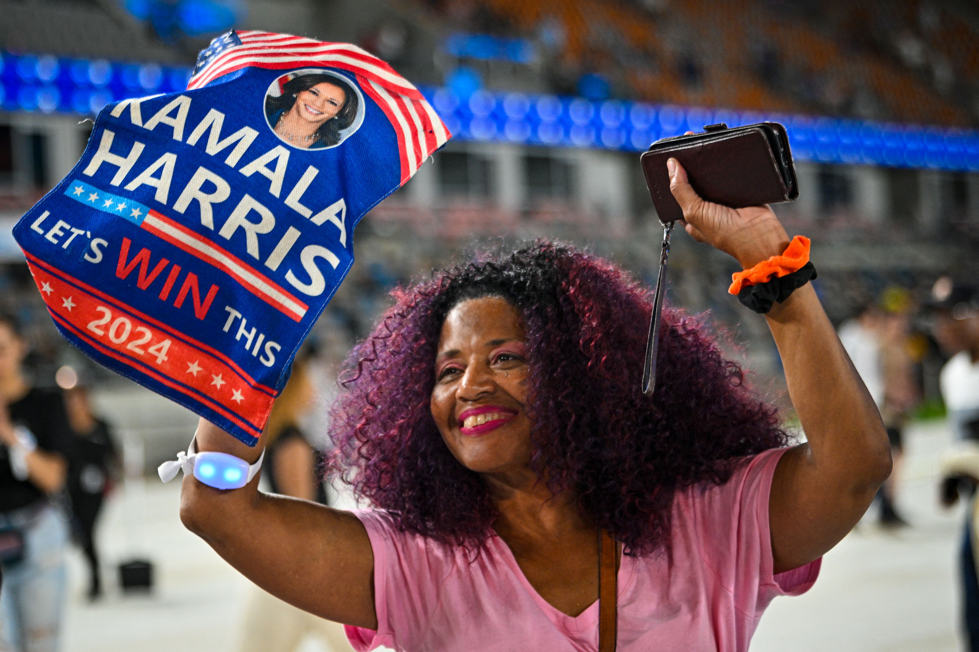 Czarnoskóra kobieta z afro trzymająca plakat „Kamala Harris, win this!"