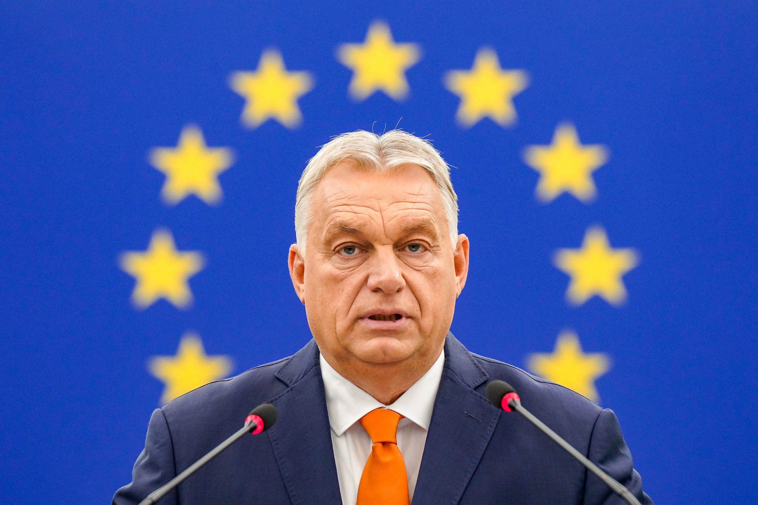 Viktor Orban sfotografowany na tle niebieskiej flagi UE; zdjęcie jest skadrowane tak, że okrąg z gwiazdek unijnej flagi układa się przy głowie premiera Węgier jak aureola.