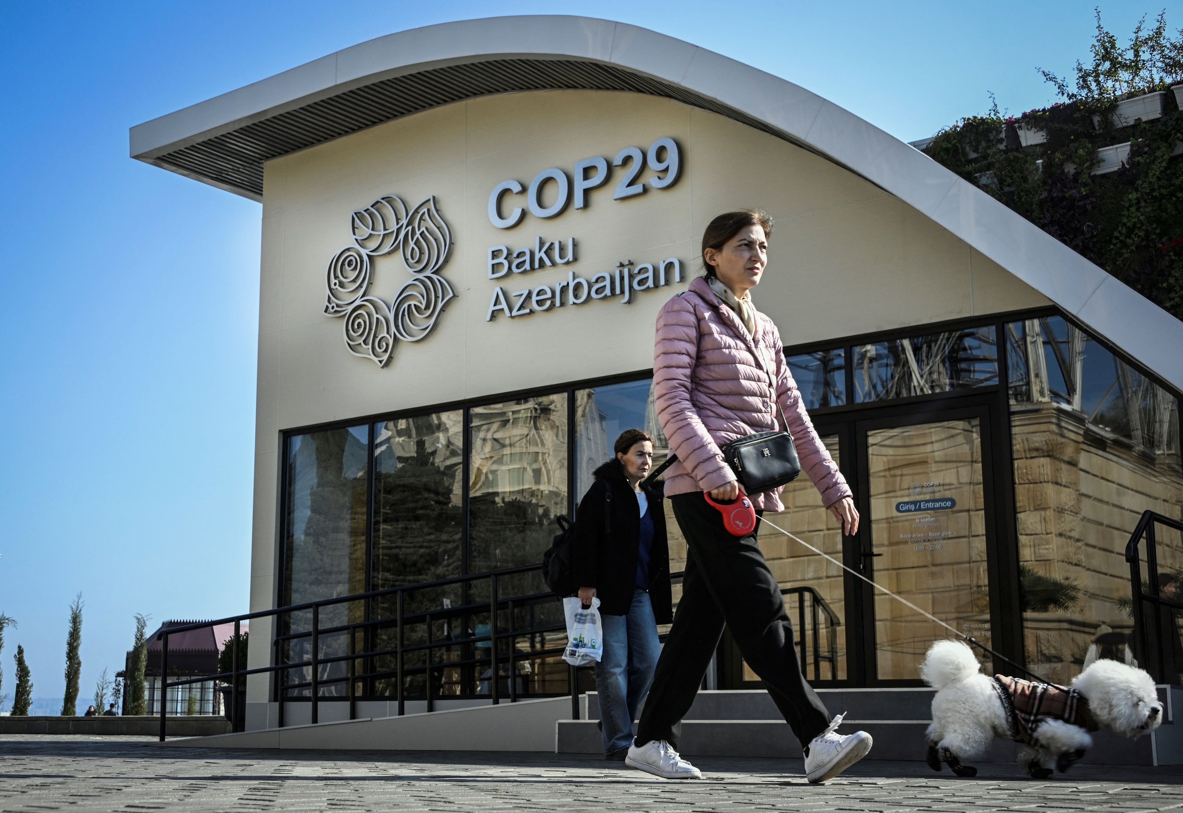 A pedestrian walks in front of the COP29 information centre in Baku on November 10, 2024, on the eve of UN Climate Change Conference. - The 2024 UN Climate Change Conference (UNFCCC COP 29) will convene from 11 to 22 November 2024 in Baku. (Photo by Alexander NEMENOV / AFP)