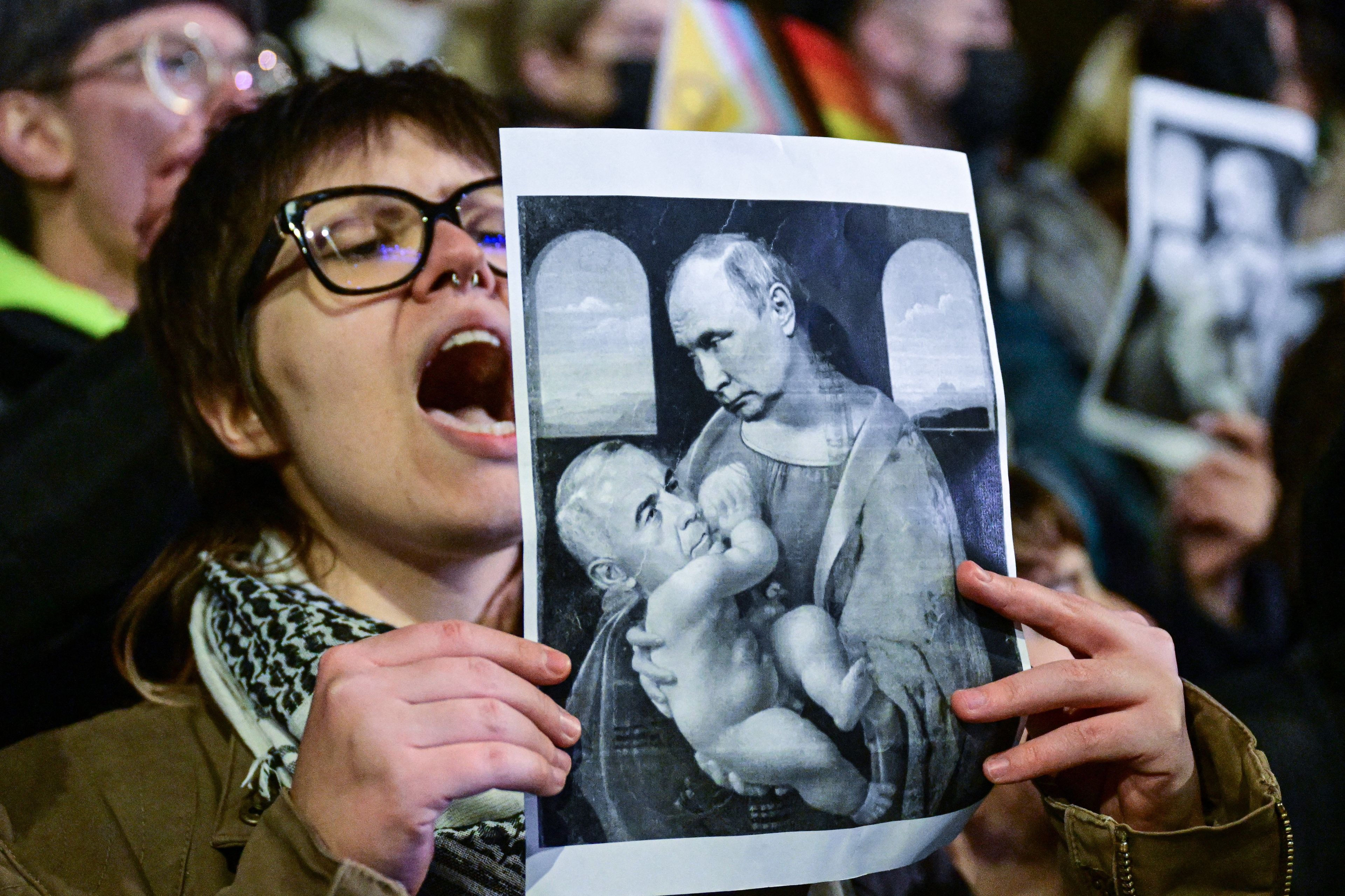 Kobieta trzyma na demostracji zdjęcie, na którym na Madonnę Leonarda da Vinci nałożono twarz Putina, a na Jezusa - Georgescu