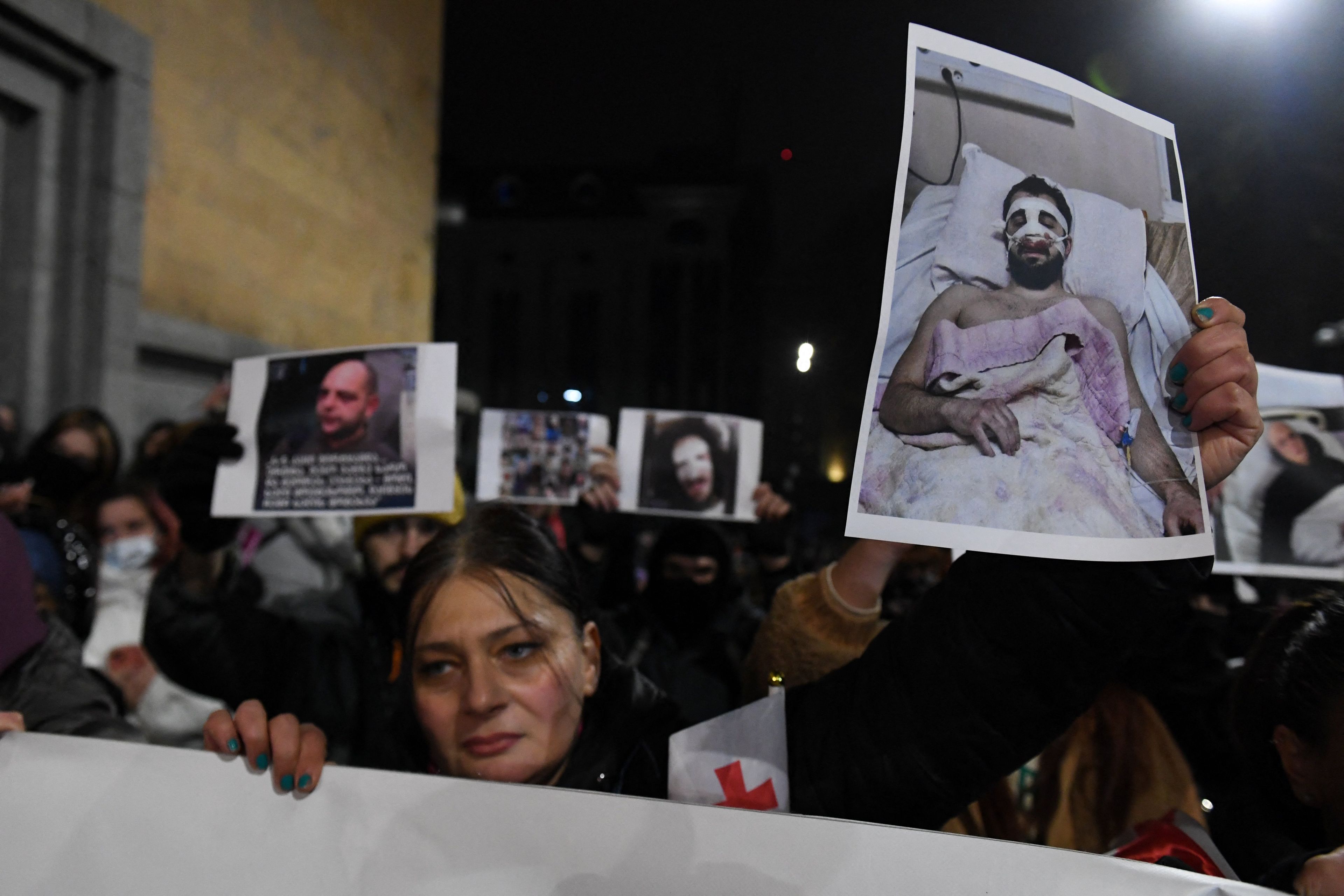 Anti-government protesters holding pictures of fellow demonstrators injured in alleged police beatings rally for a tenth consecutive day of mass demonstrations against the government's postponement of European Union accession talks until 2028, in central Tbilisi on December 7, 2024. (Photo by KAREN MINASYAN / AFP)