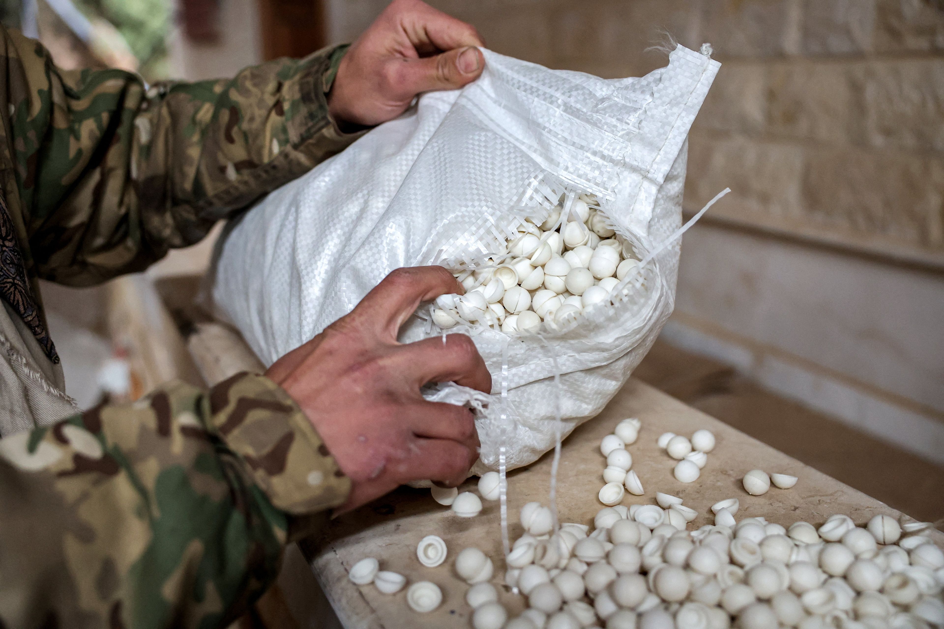 A Syrian rebel fighter inspects pills of Captagon (brand name of psychostimulant drug Fenethylline) produced at a makeshift lab facility at a ranch villa in the town of al-Dimas about 27 kilometres northwest of Damascus on December 22, 2024. - The dramatic collapse of Bashar al-Assad's Syrian regime has thrown light into many of the dark corners of his rule, including the industrial-scale export of the banned drug Captagon. Victorious Islamist fighters have seized military bases and distribution hubs for the amphetamine-laced stimulant, which has flooded the black market across the Middle East. (Photo by OMAR HAJ KADOUR / AFP)