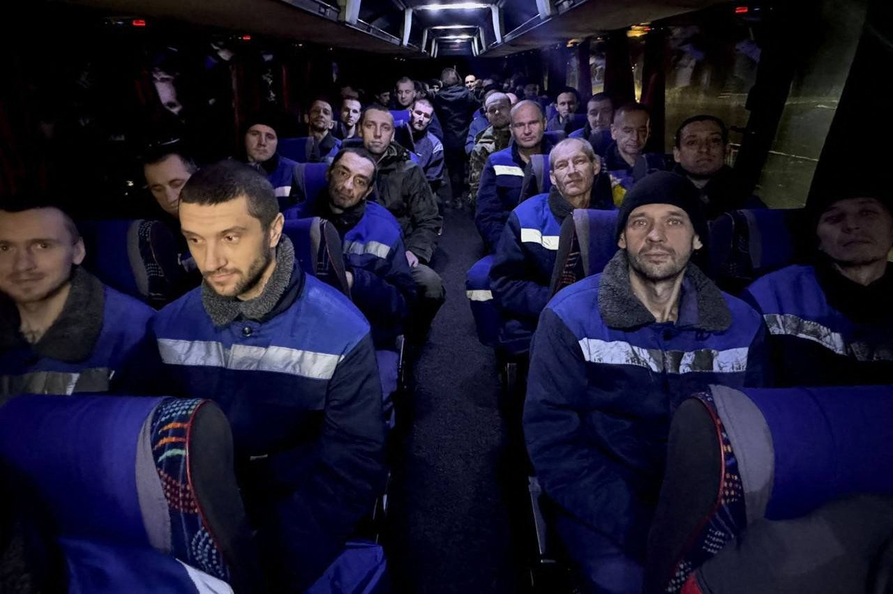 Wychudzeni mężczyźni w jednakowych ciemnych kurtkach siedza w autobusie