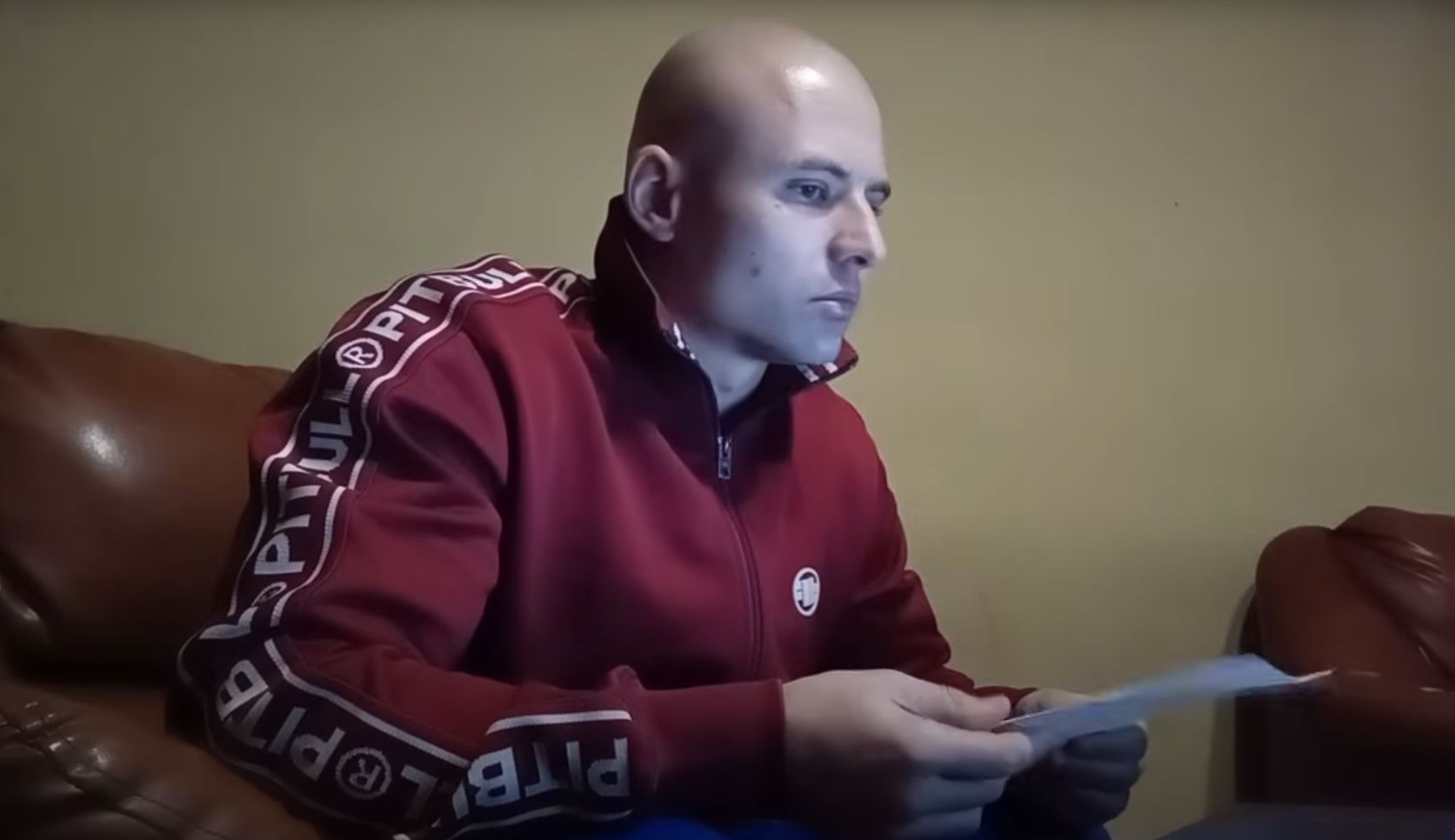 Rafał Podejma, inicjator tworzenia "patroli obywatelskich". Młody mężczyzna, łysy, w czerwonej bluzie dresowej, w ręku trzyma kartkę papieru.