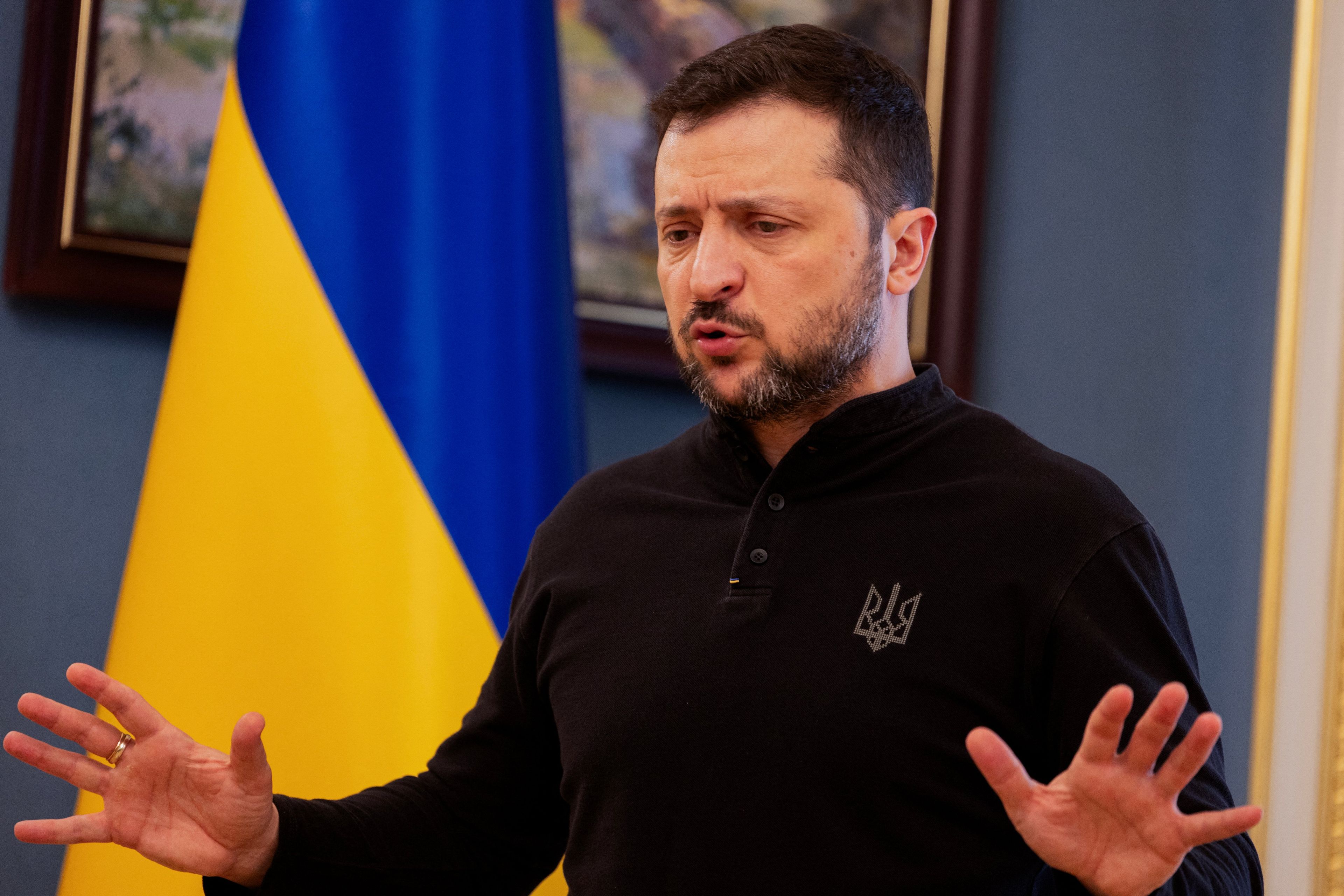 Mężczyzna stoi i przemawiając rozkłada ręce