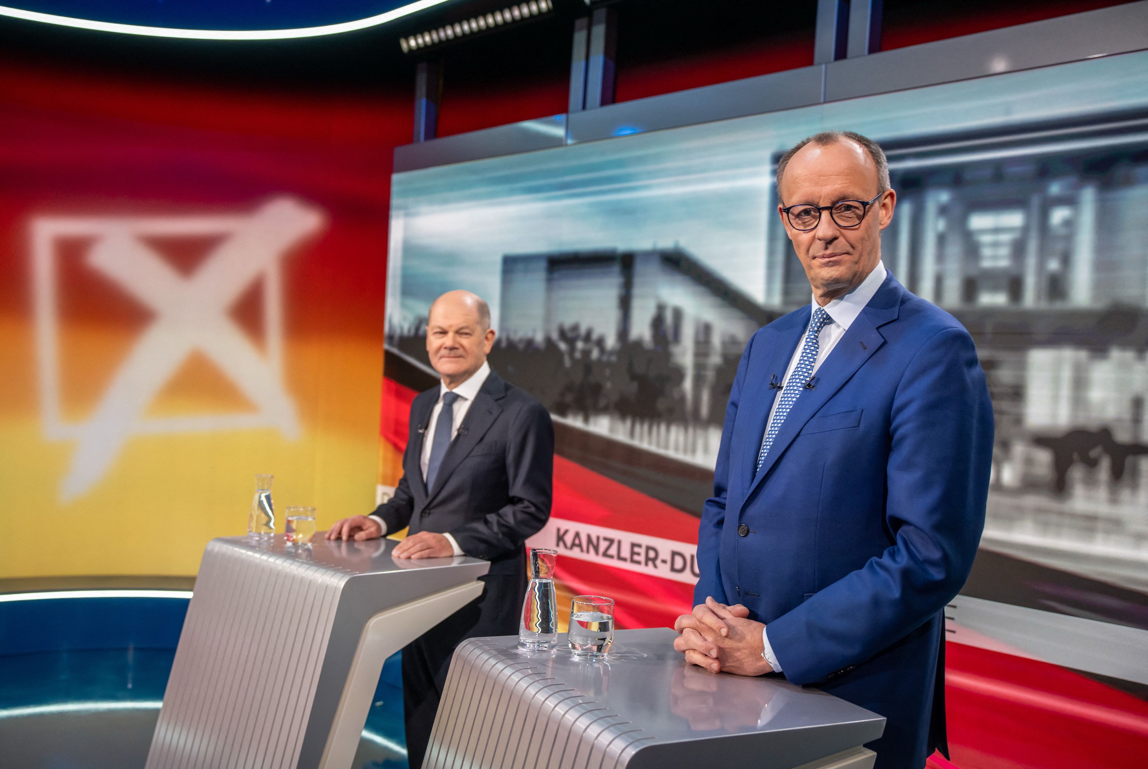 Dwaj mężczyźni w garniturach przy pulpitach telewizyjnych podczas debaty
