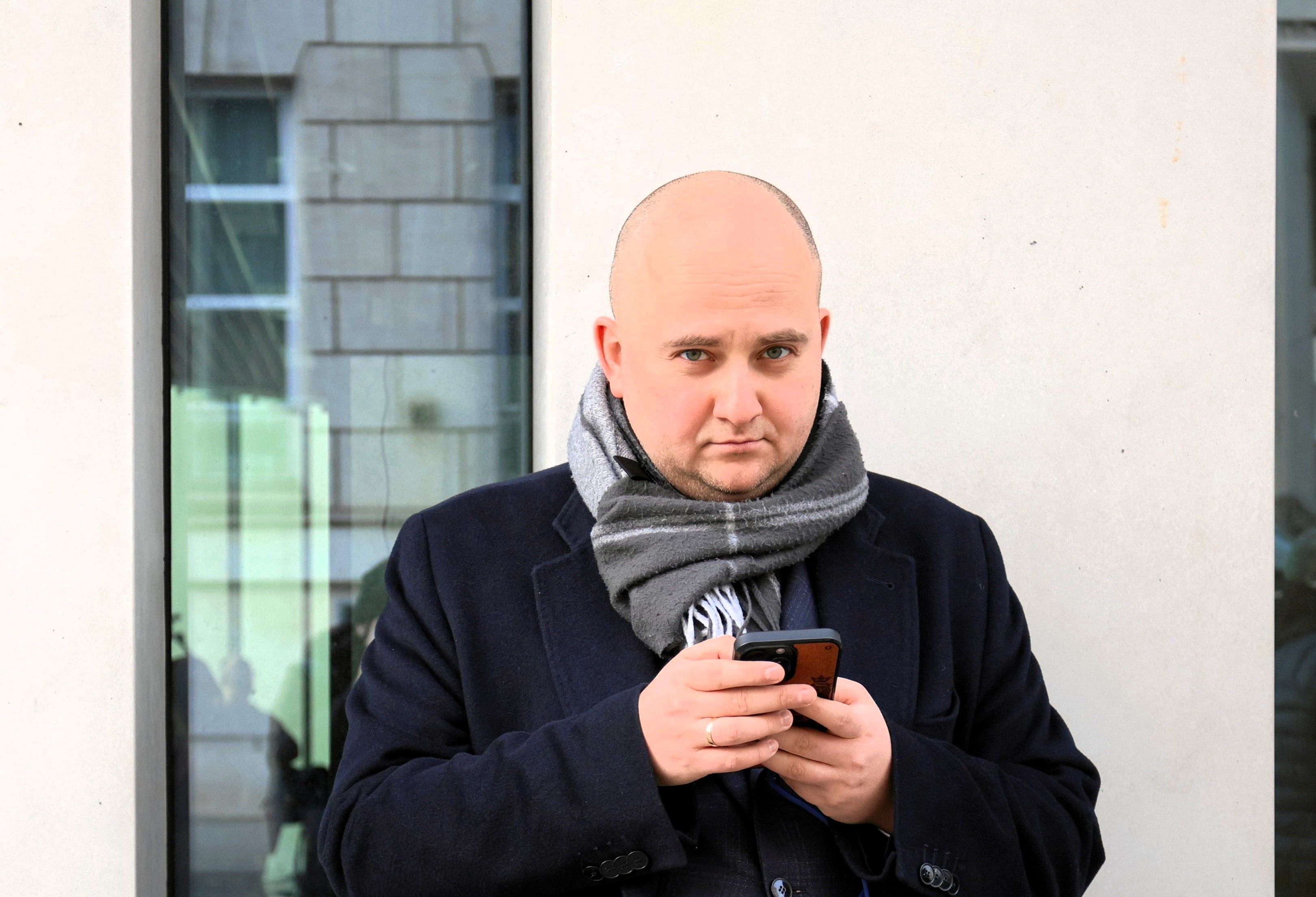 Łysyu mężczyzna w okulrach trzma w ręku telefon komórkowy, Dariusz Matecki